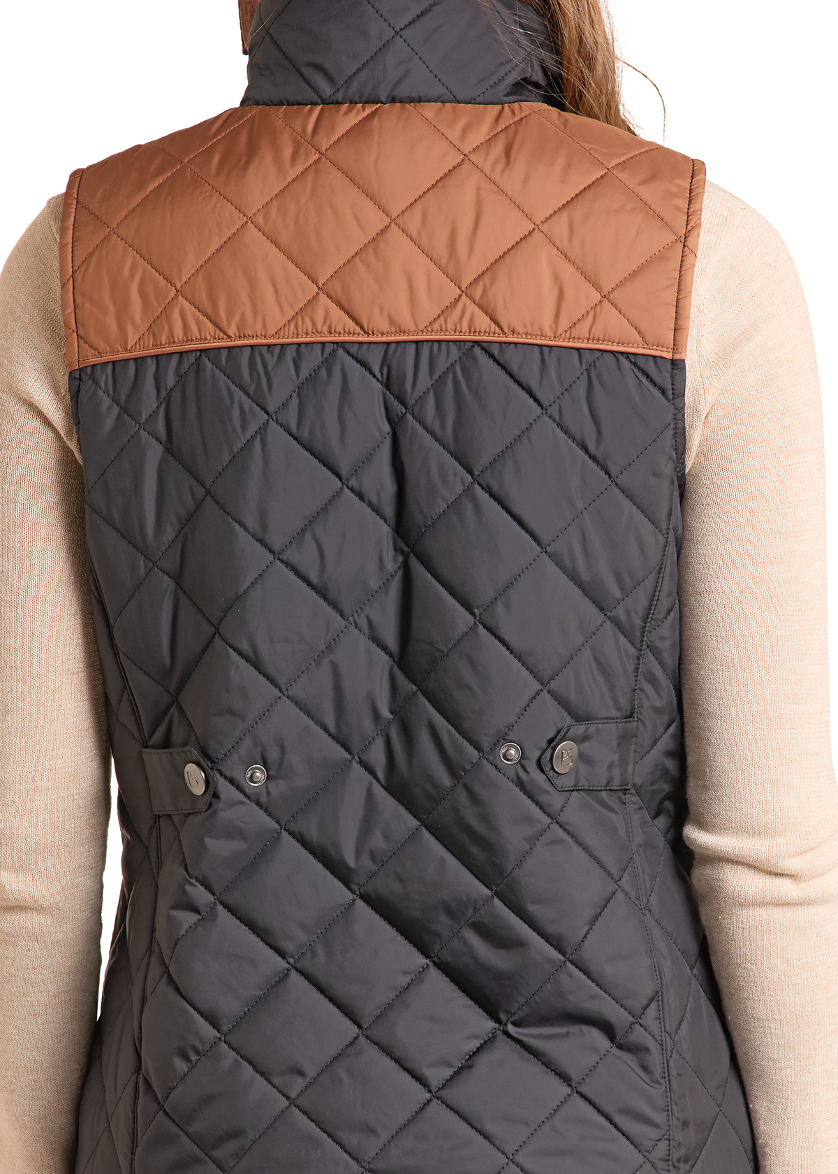 Back view of a sleeveless quilted puffer vest worn over a beige long-sleeve top.