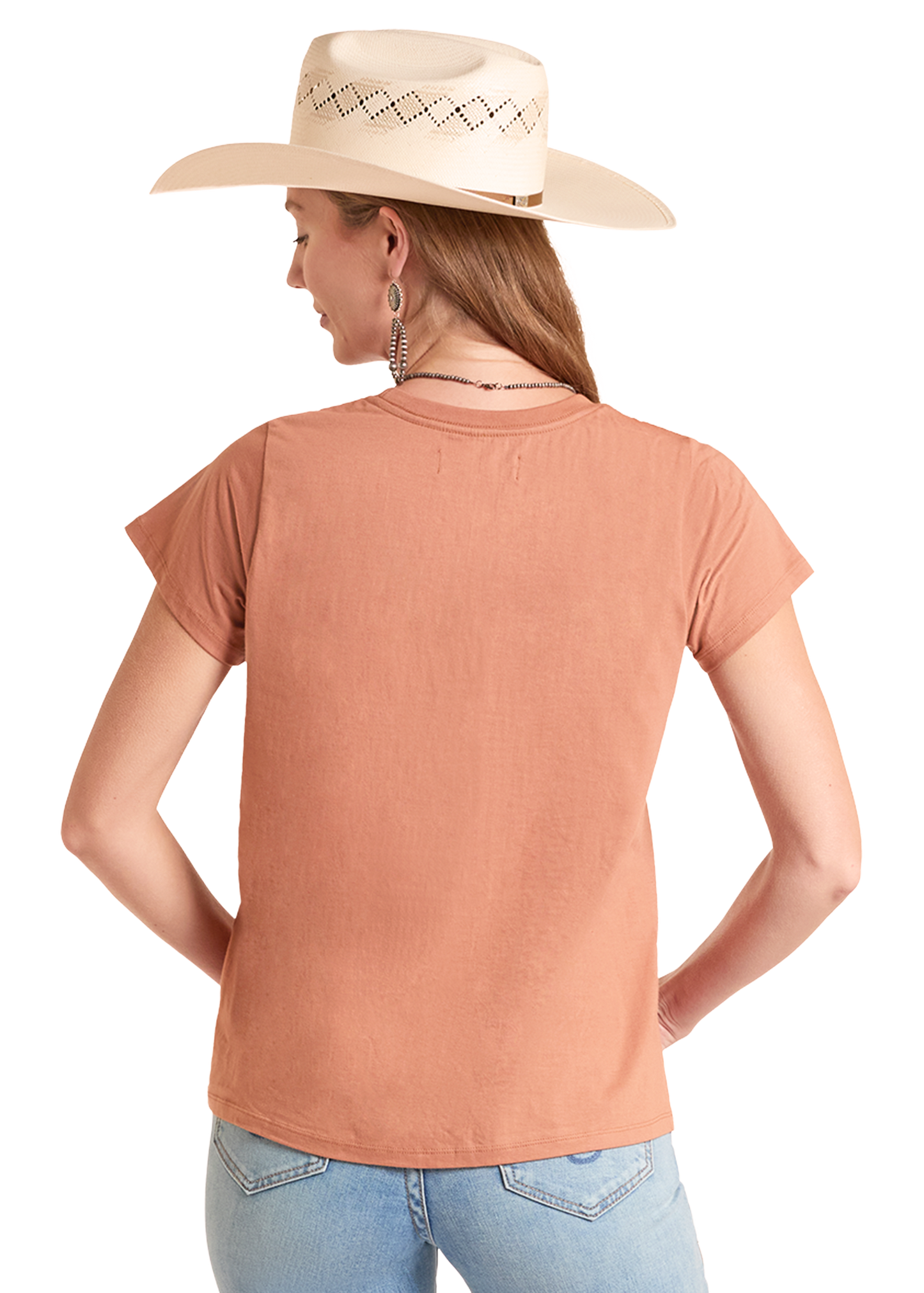 Woman wearing a peach-colored t-shirt and light blue jeans with a beige cowboy hat on a white background