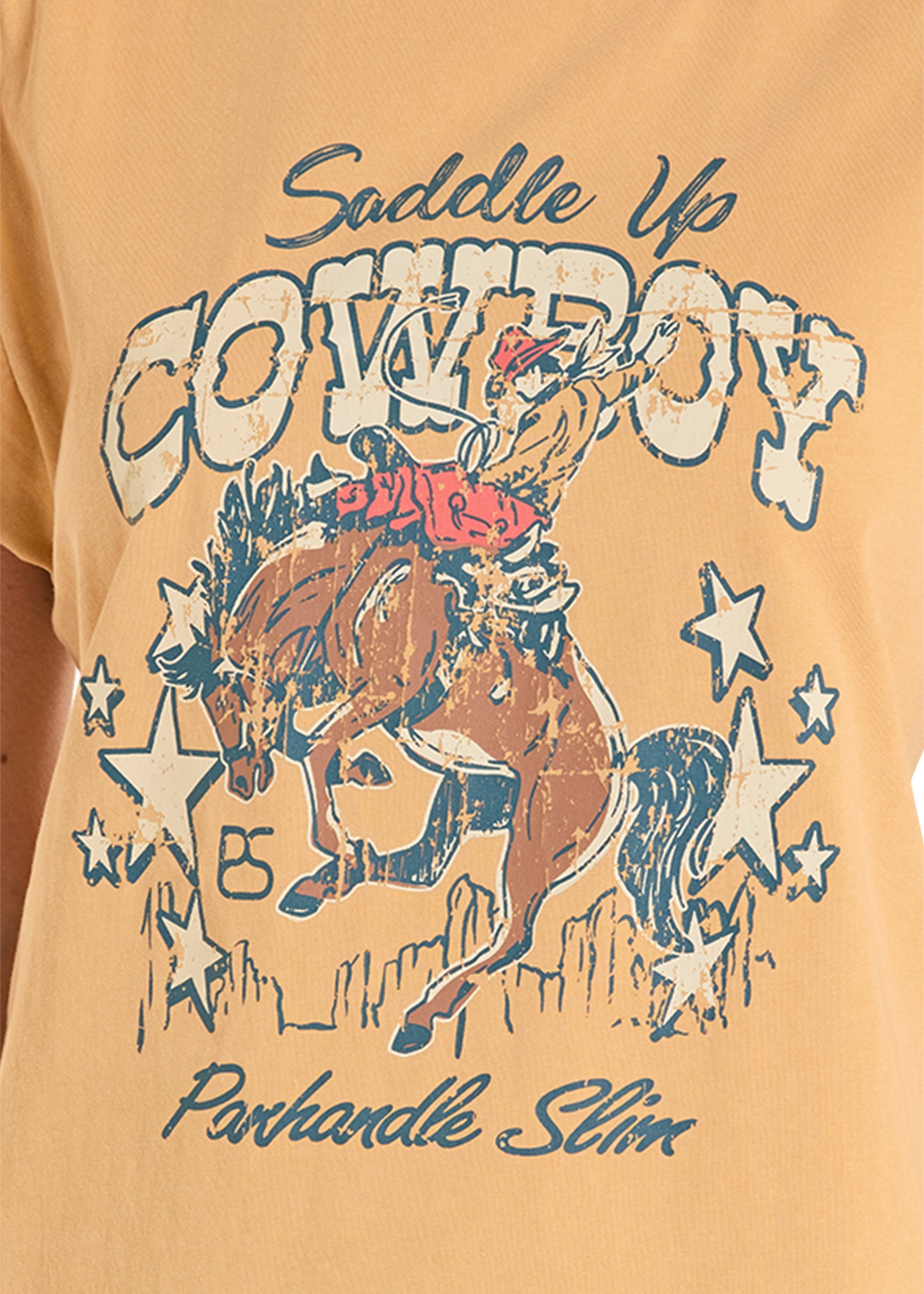 Beige t-shirt with graphic of a cowboy on a horse and 'Saddle Up Cowboy' text.