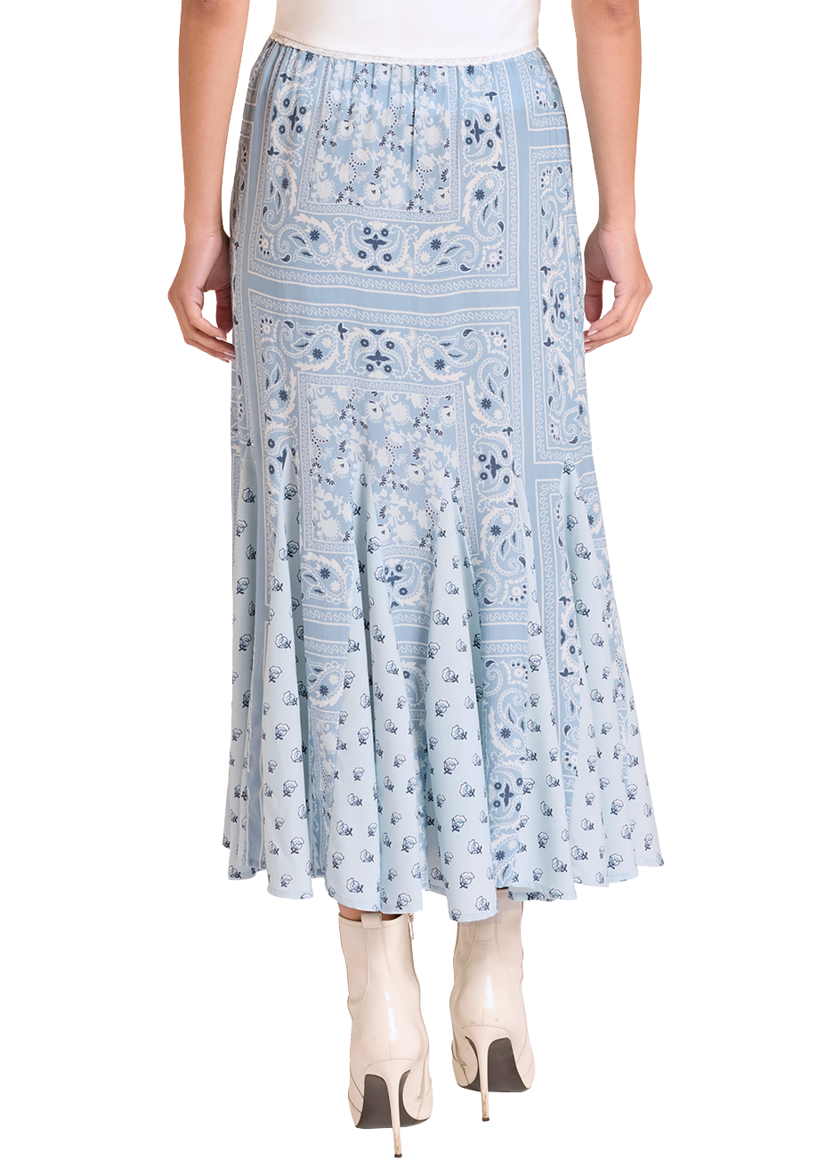 Woman wearing a white sleeveless top and light blue floral skirt with a beige hat on a white background