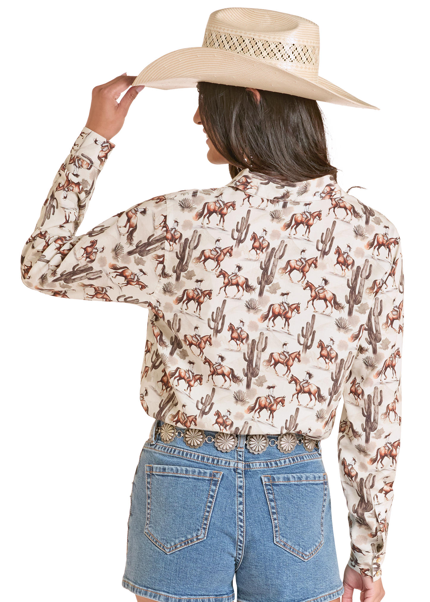 Person wearing a patterned shirt with horses and cacti, holding a cowboy hat on a white background