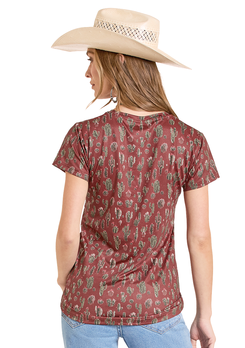 Woman wearing a patterned red shirt and light blue jeans with a cowboy hat on a white background