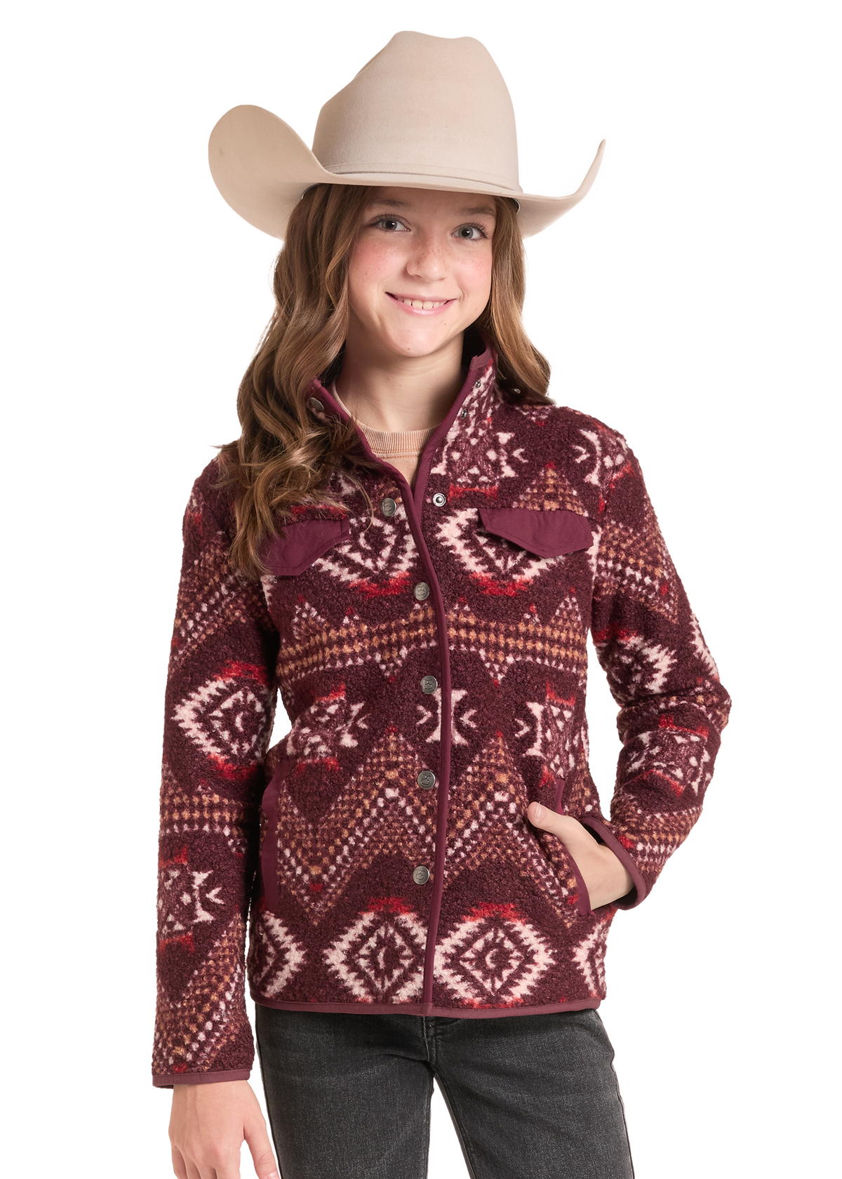 A young girl wearing a beige cowboy hat and a maroon southwestern patterned fleece jacket, paired with black jeans.