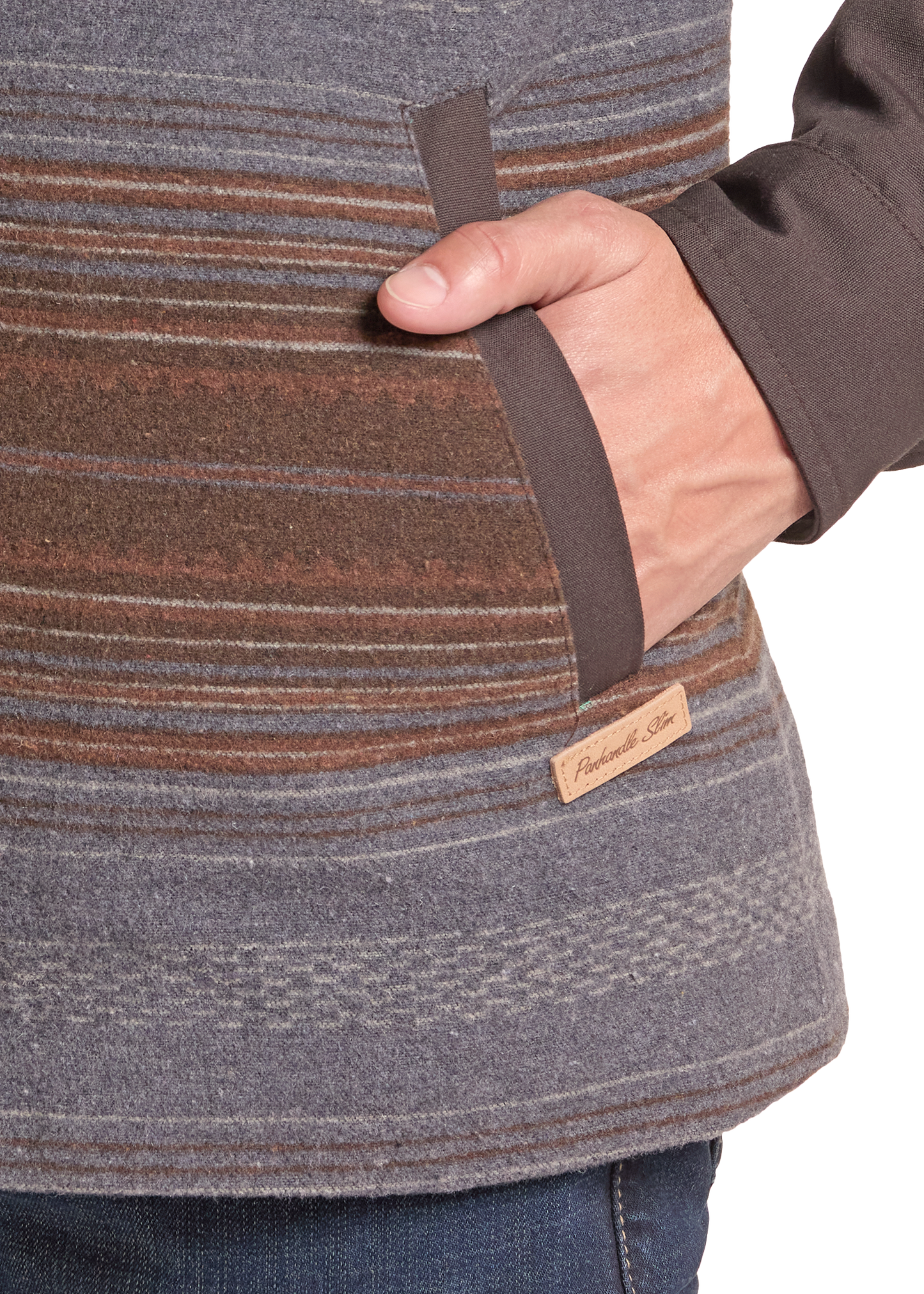 Close-up of a person wearing a striped fleece jacket in gray, brown, and rust tones, with a hand inserted into a side pocket.