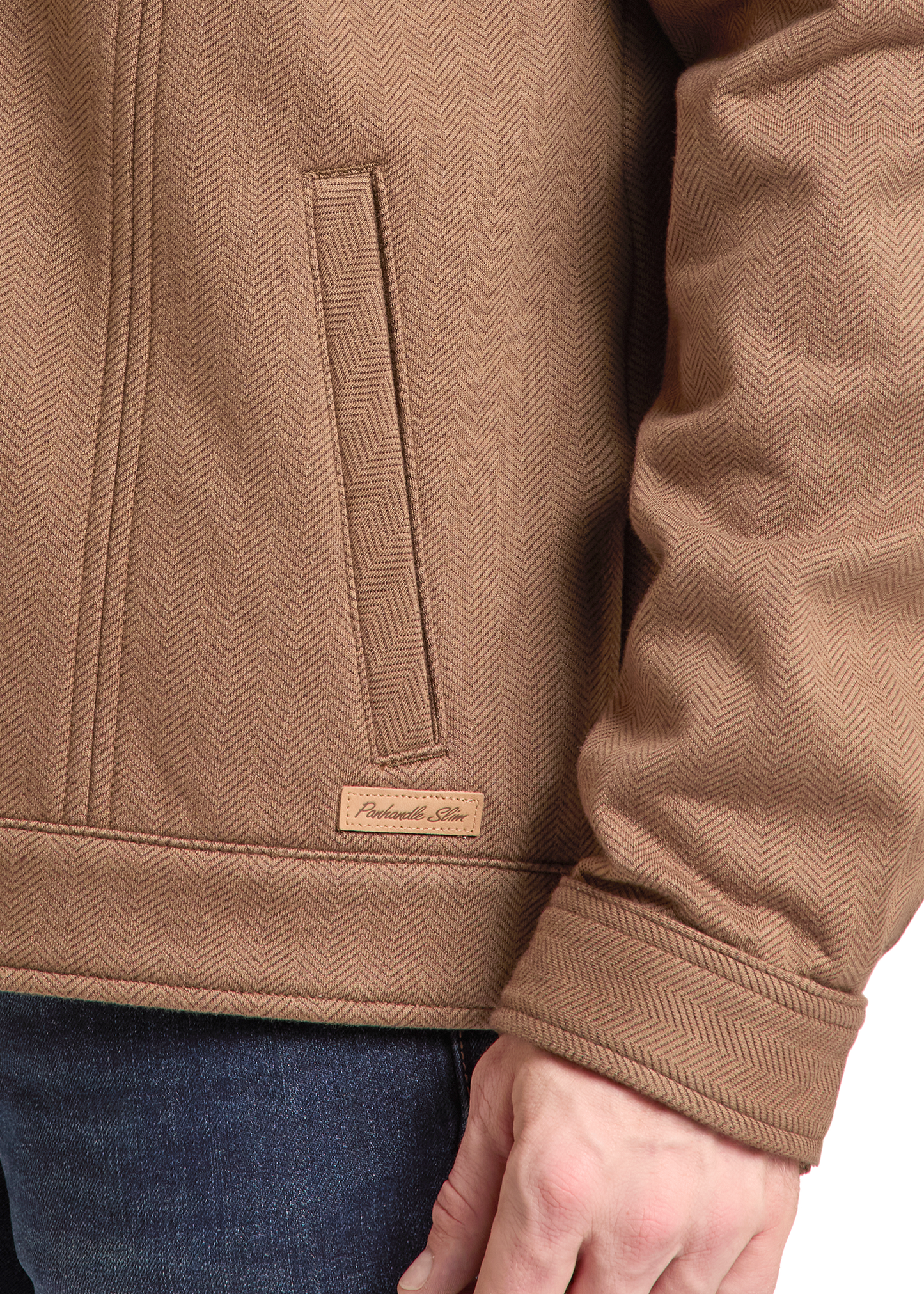 Close-up of a person wearing a tan herringbone jacket, showing the chest pocket, cuff, and a small leather patch with the brand name 'Pembrook Co.'.