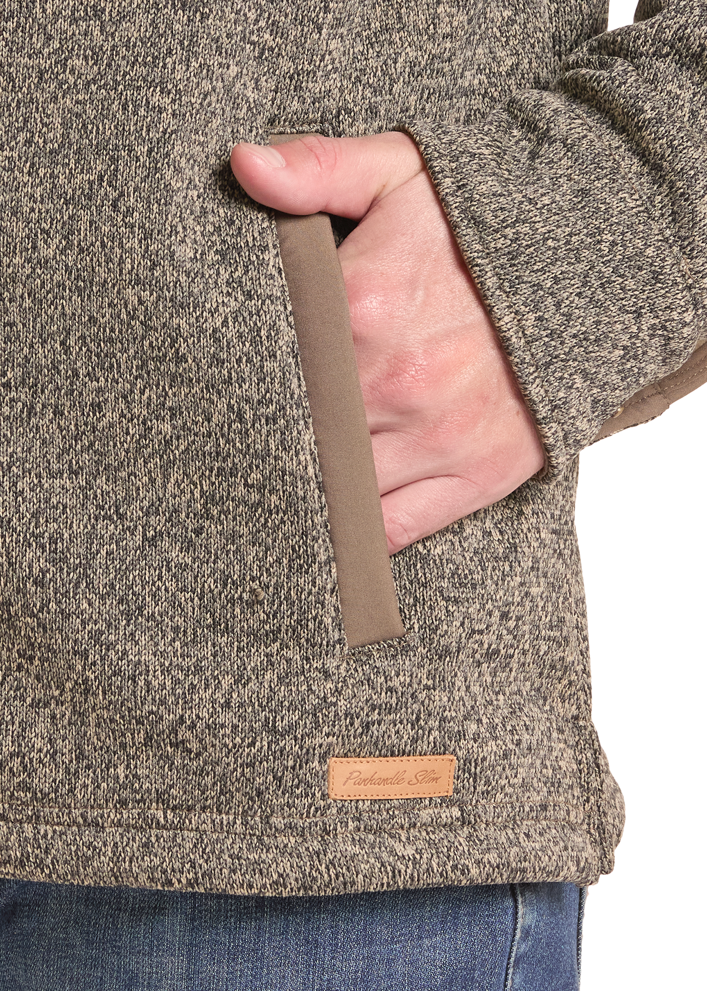 Close-up of a person wearing a heathered taupe-brown fleece jacket with a side pocket, hand in pocket, and a small tan brand patch near the hem.