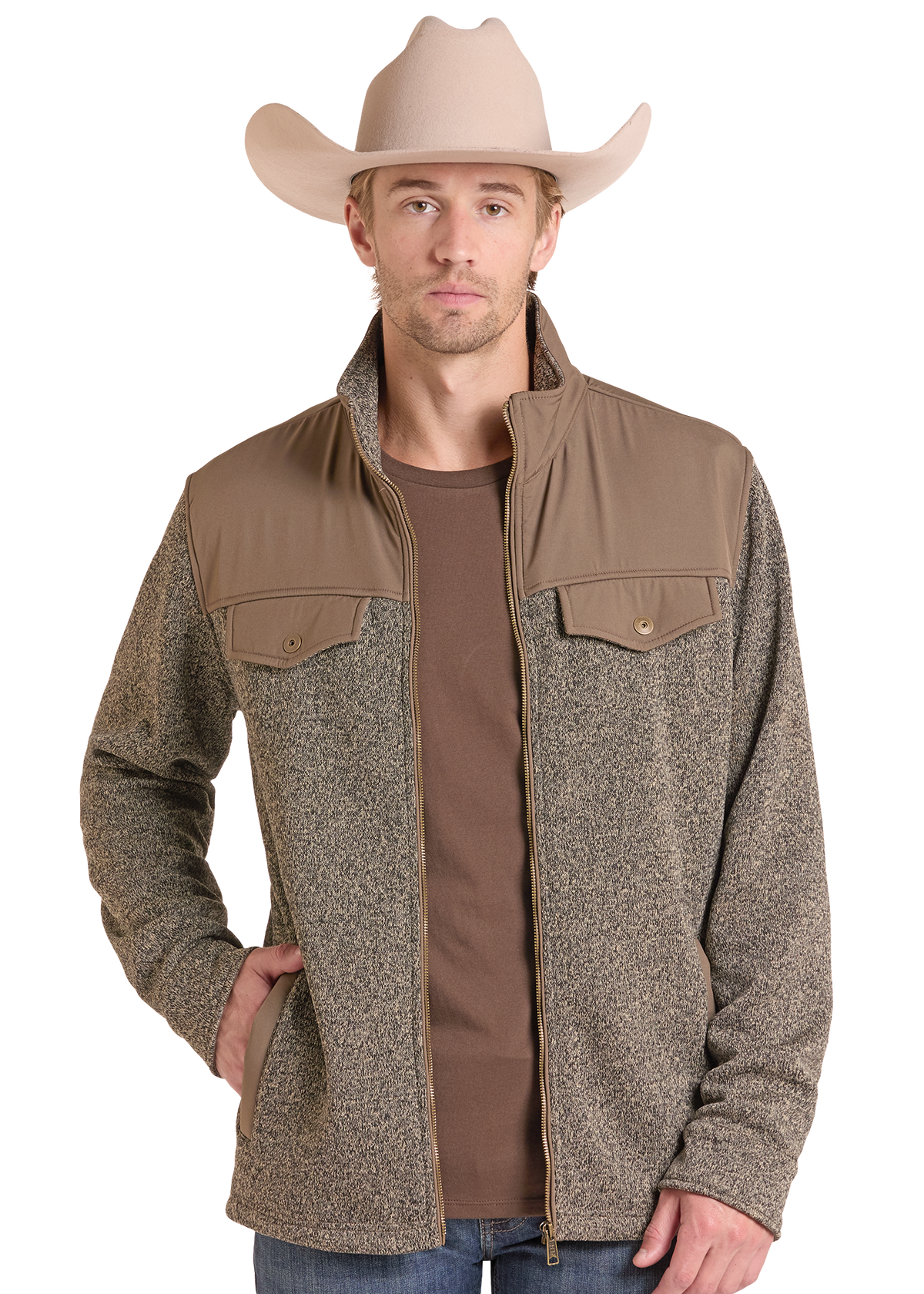 A man wearing a tan cowboy hat and a zip-front jacket with a heathered taupe-brown body and smooth tan shoulder yokes, layered over a brown t-shirt and blue jeans.