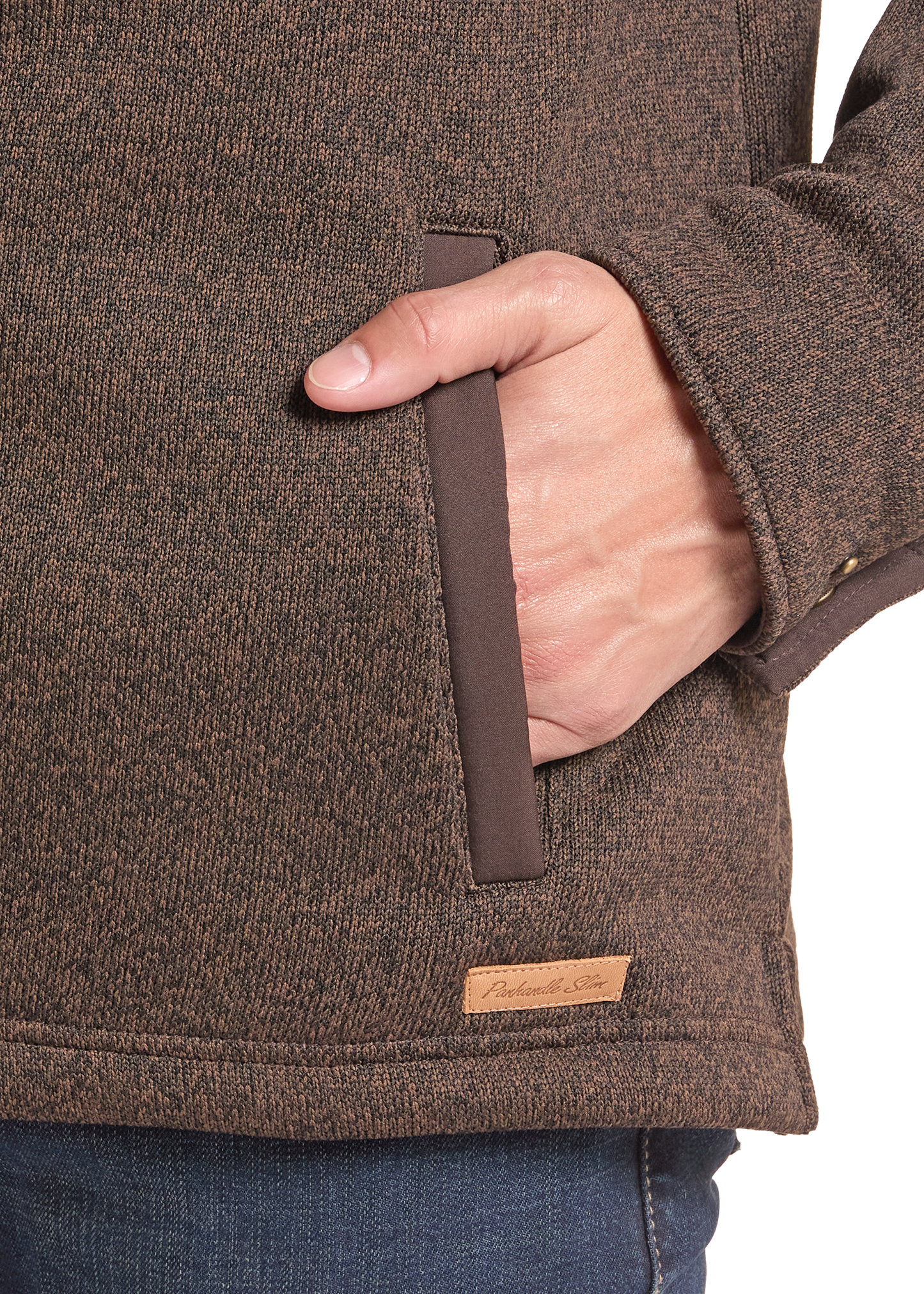 Close-up of a person wearing a brown textured fleece jacket, showing a side pocket with a brown pull tab and a small tan brand label.
