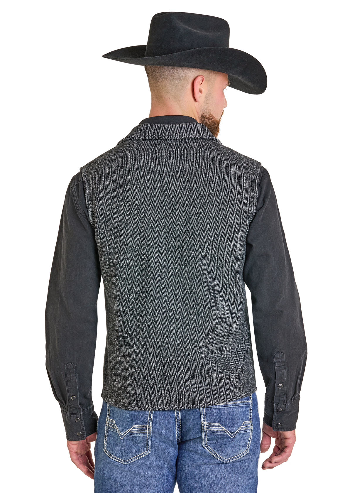 A man shown from the back wearing a dark gray textured vest over a black long-sleeve shirt, blue jeans, and a black cowboy hat.
