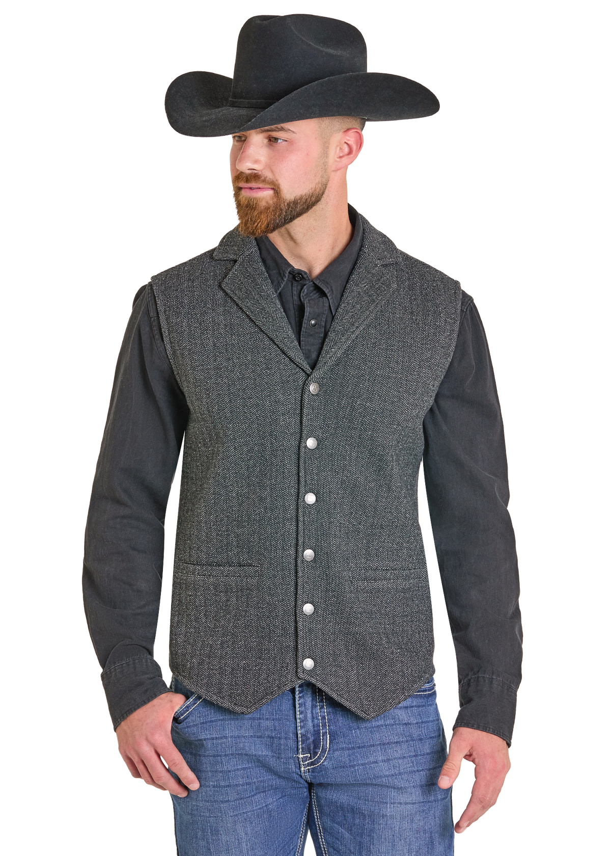 A man wearing a dark gray textured western vest over a black long-sleeve shirt, blue jeans, and a black cowboy hat, shown against a plain white background.