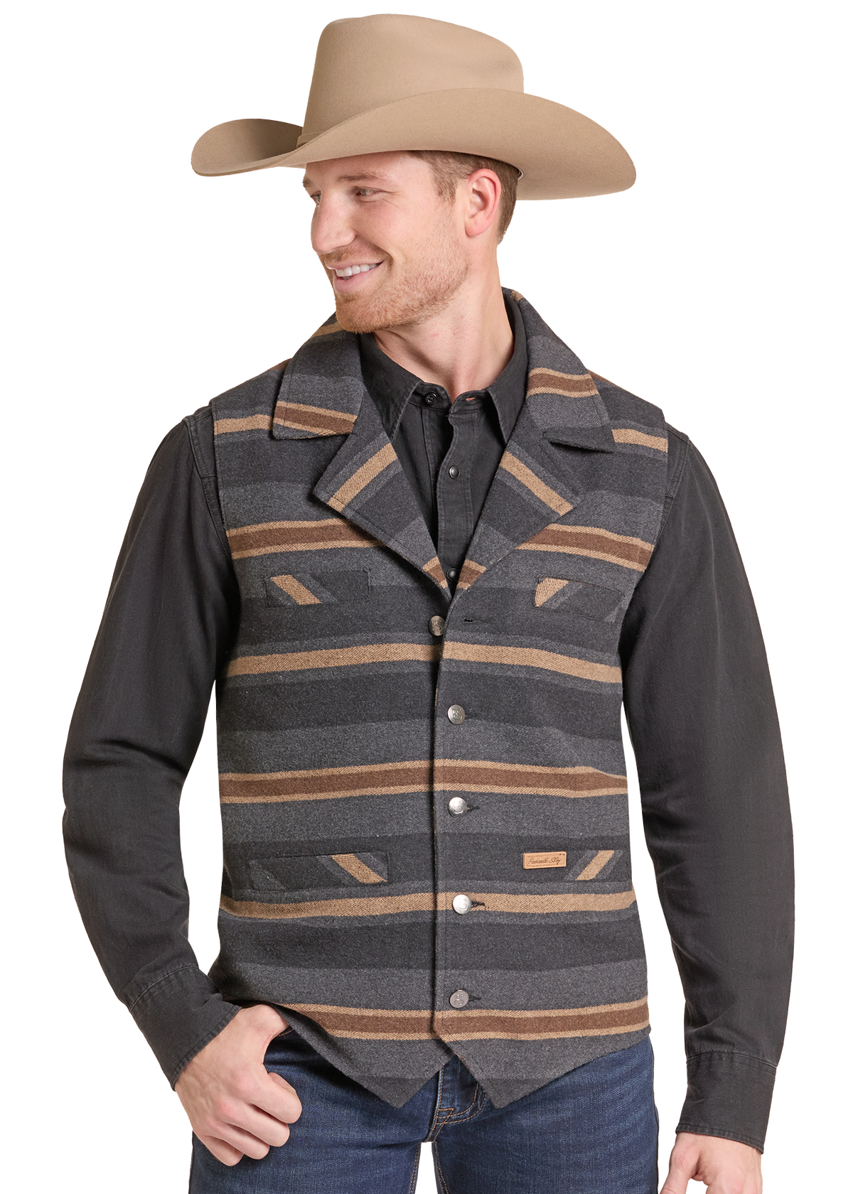 A man wearing a tan cowboy hat, a dark charcoal long-sleeve shirt, and a gray striped western vest with brown and tan stripes, paired with blue jeans.