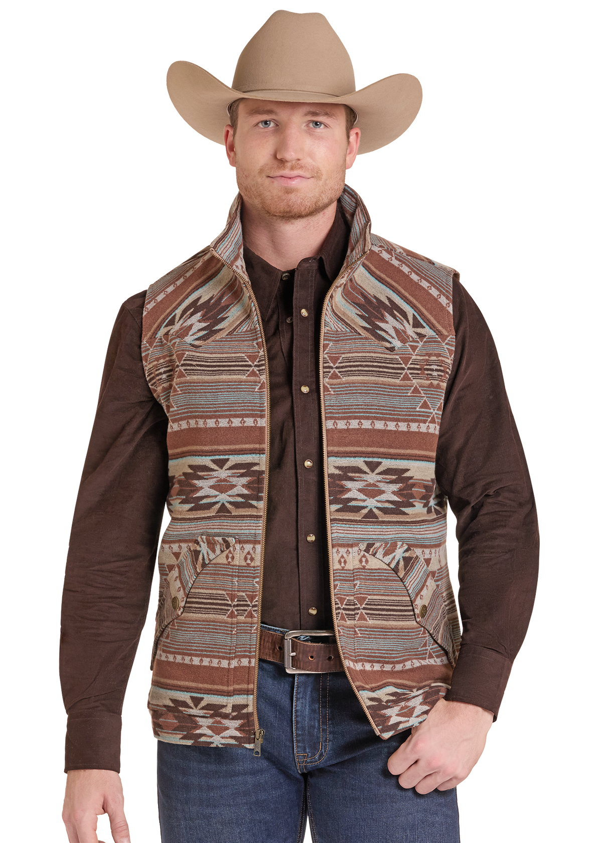 A man wearing a brown western vest with a Southwestern geometric pattern, a brown long-sleeve shirt, blue jeans, and a tan cowboy hat.