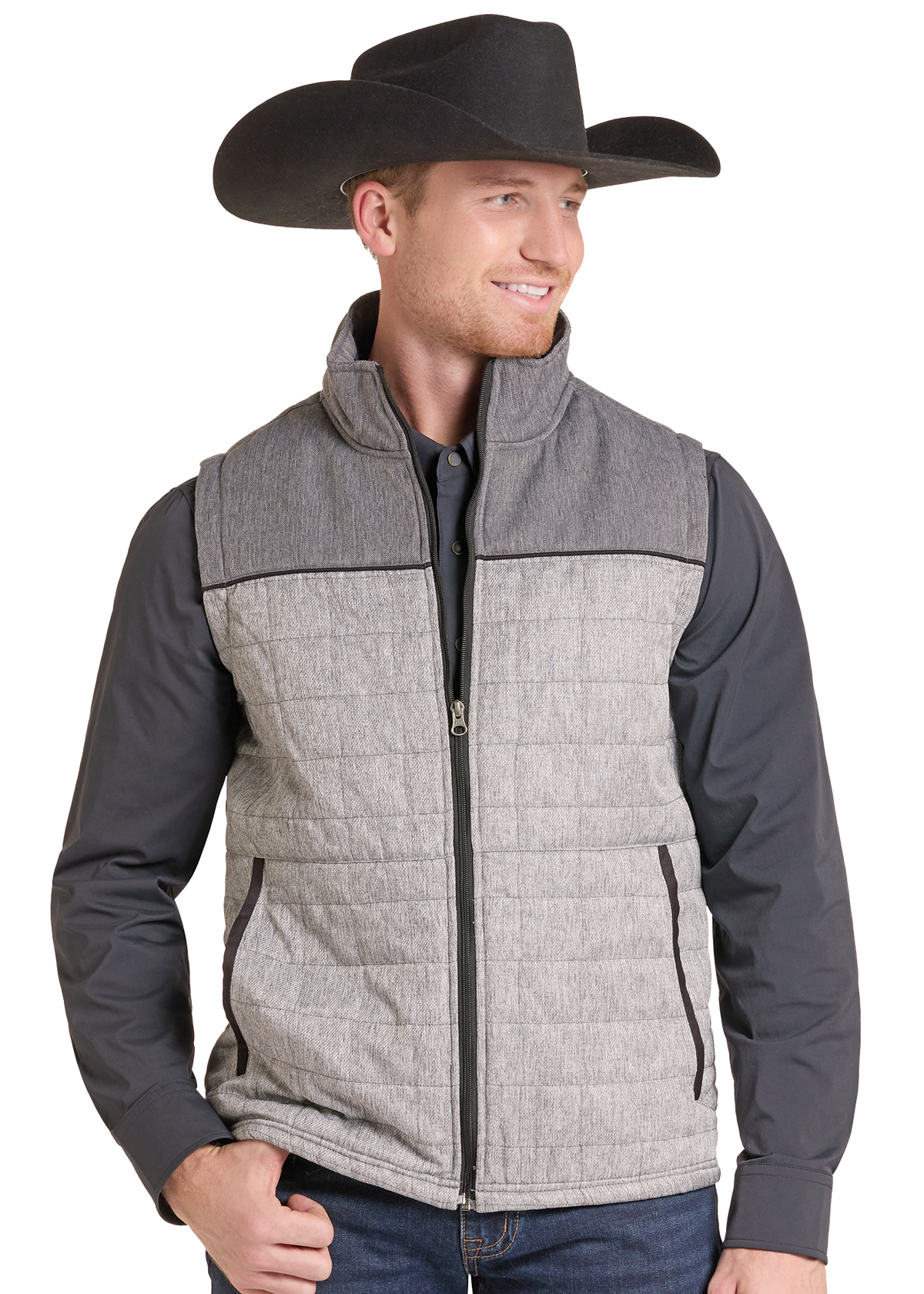 A man wearing a gray quilted zip-front vest over a dark gray long-sleeve shirt and a black cowboy hat.