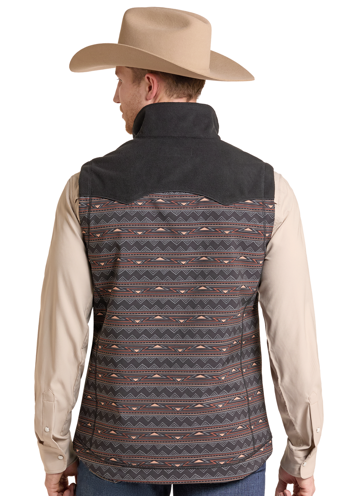 Rear view of a man wearing a western vest over a beige long-sleeve shirt and blue jeans, with a tan cowboy hat. The vest has a dark charcoal gray suede-like shoulder yoke and a patterned body in dark gray, black, and rust orange geometric stripes.