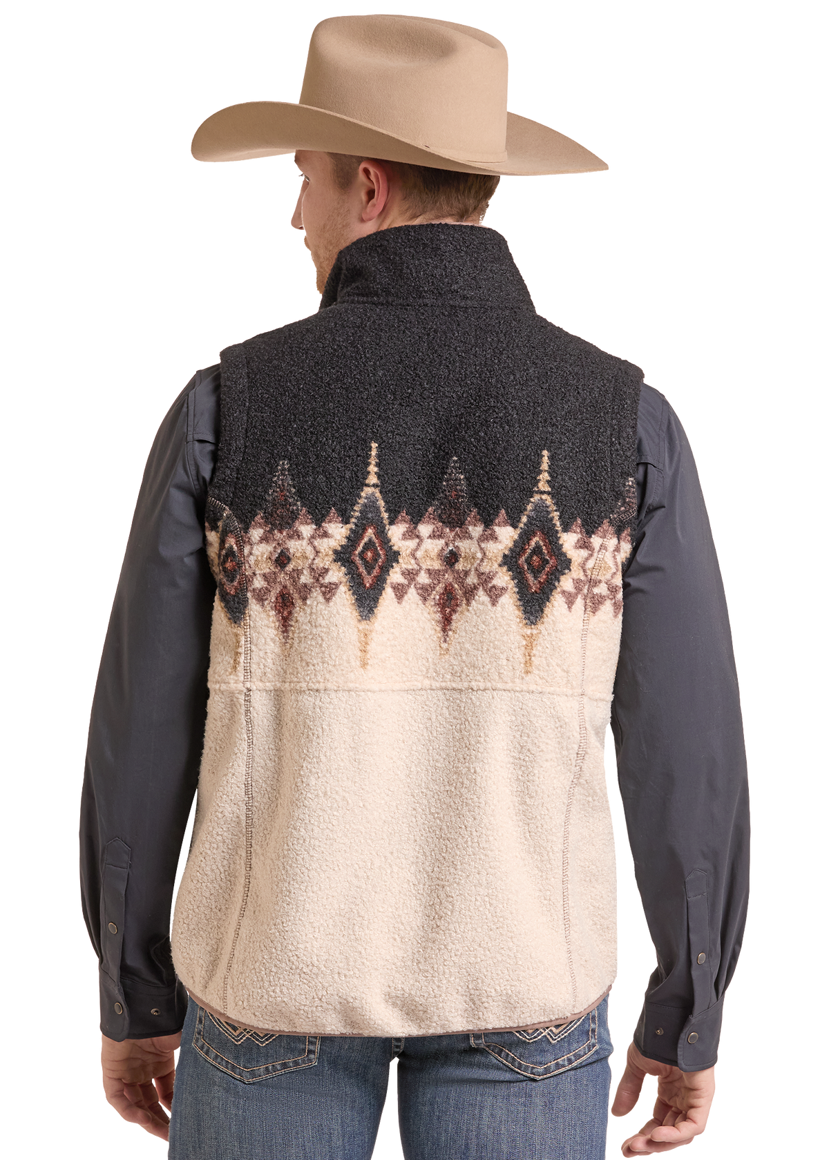 A man shown from the back wearing a sherpa-lined vest with a dark gray upper section and a cream lower section featuring a brown and beige geometric pattern. He is also wearing a tan cowboy hat, a dark gray long-sleeve shirt, and blue jeans.