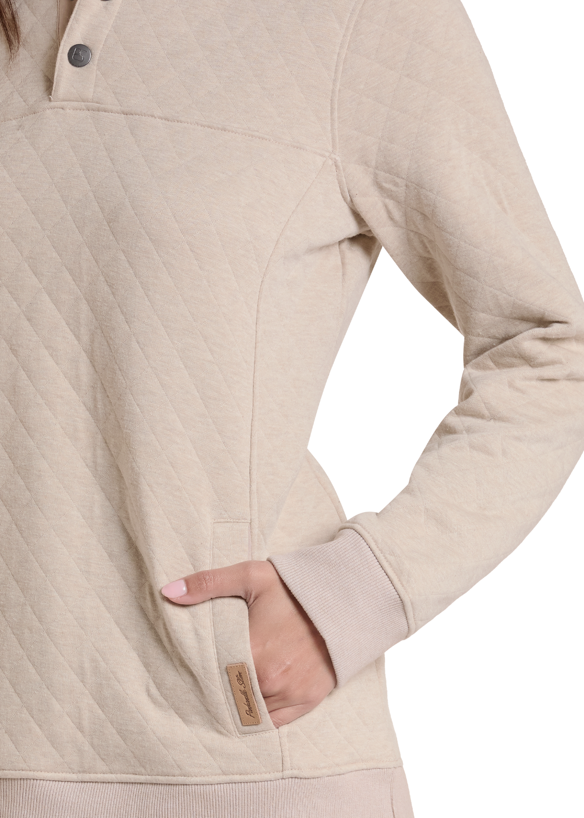 Close-up of a person wearing a quilted long-sleeve pullover in a light warm beige color. The image shows the chest, sleeve, pocket, and hand area.