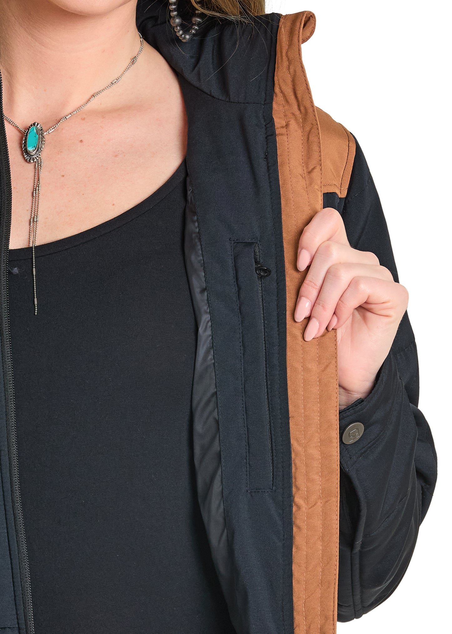 Person wearing a black and brown jacket with a necklace featuring a turquoise stone.