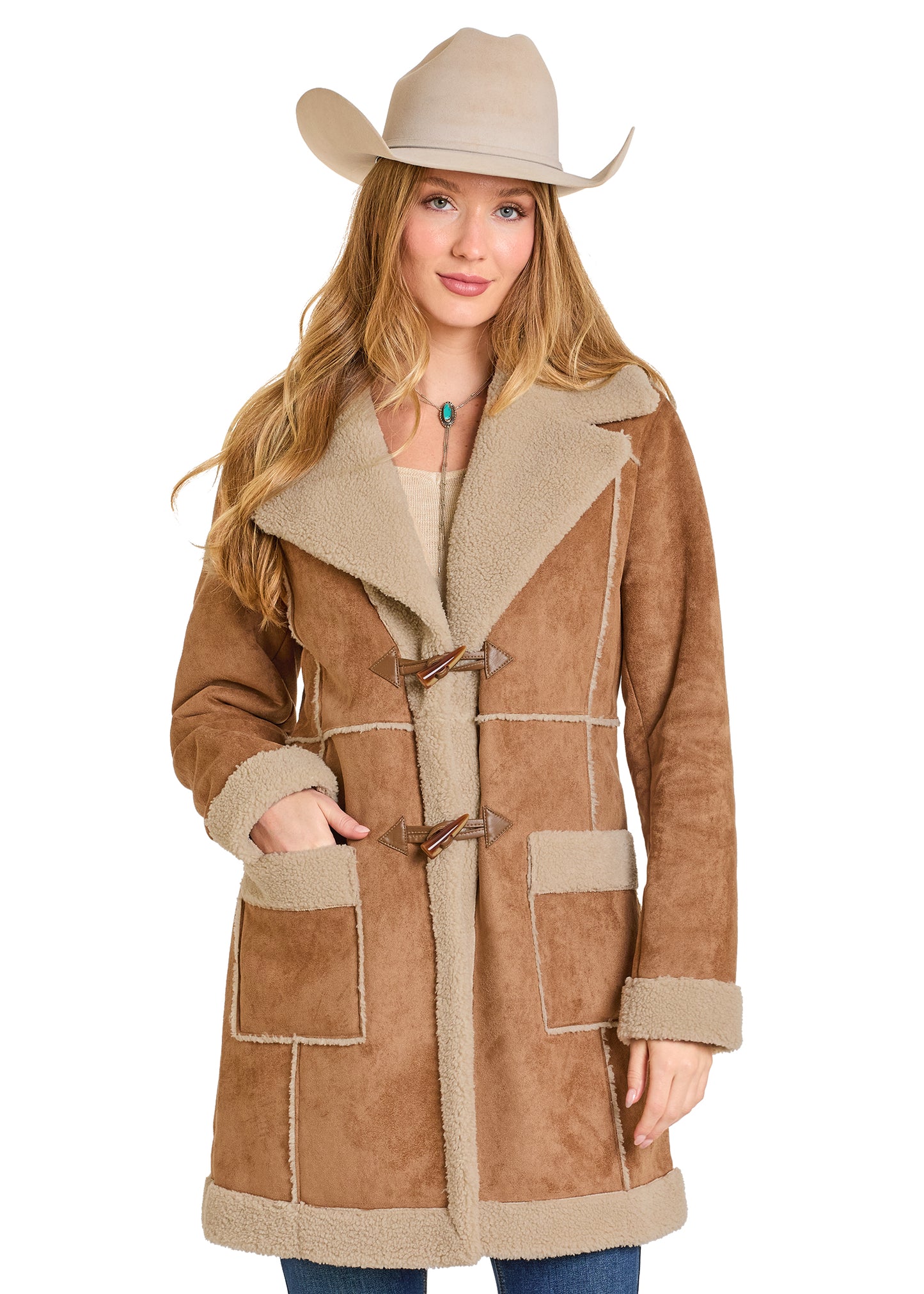 Woman wearing a brown shearling coat with beige lining and a cowboy hat on a white background