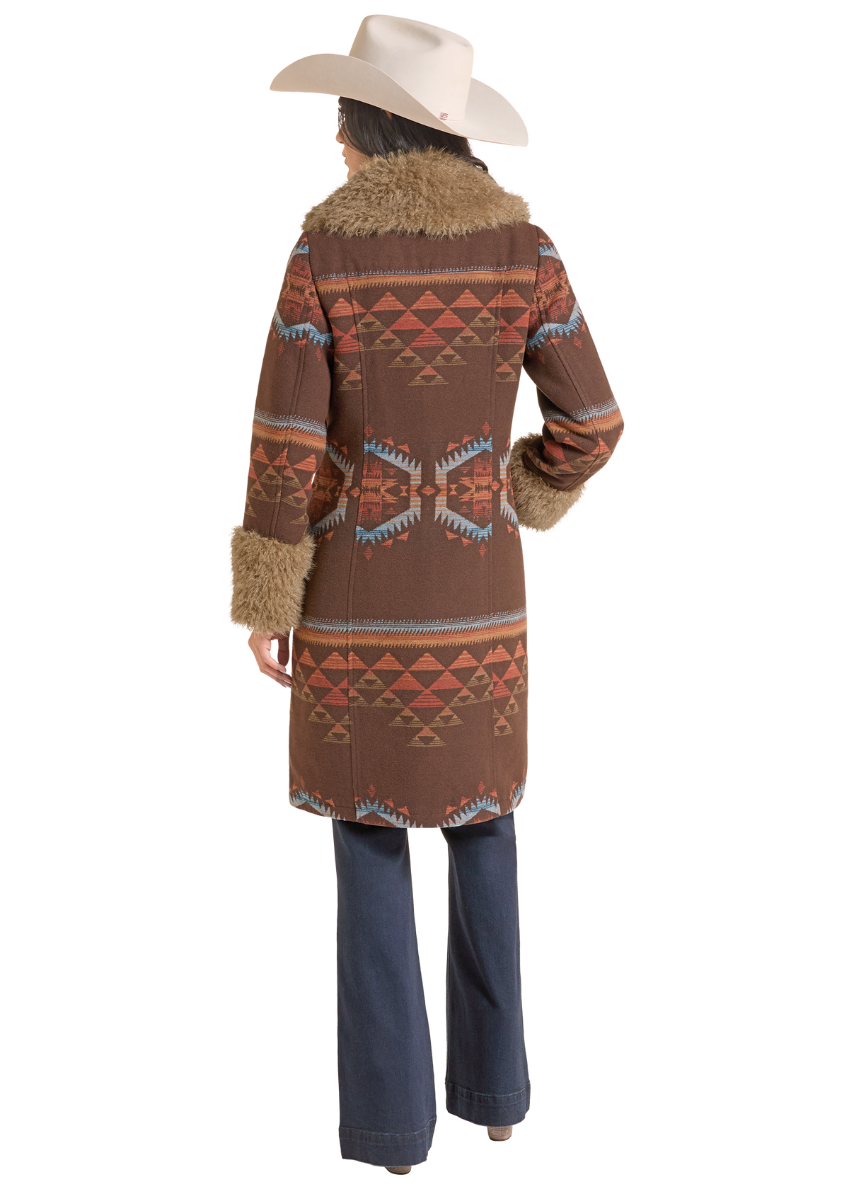 A woman shown from the back wearing a brown patterned coat with faux fur trim, a cream cowboy hat, and dark blue flared jeans.