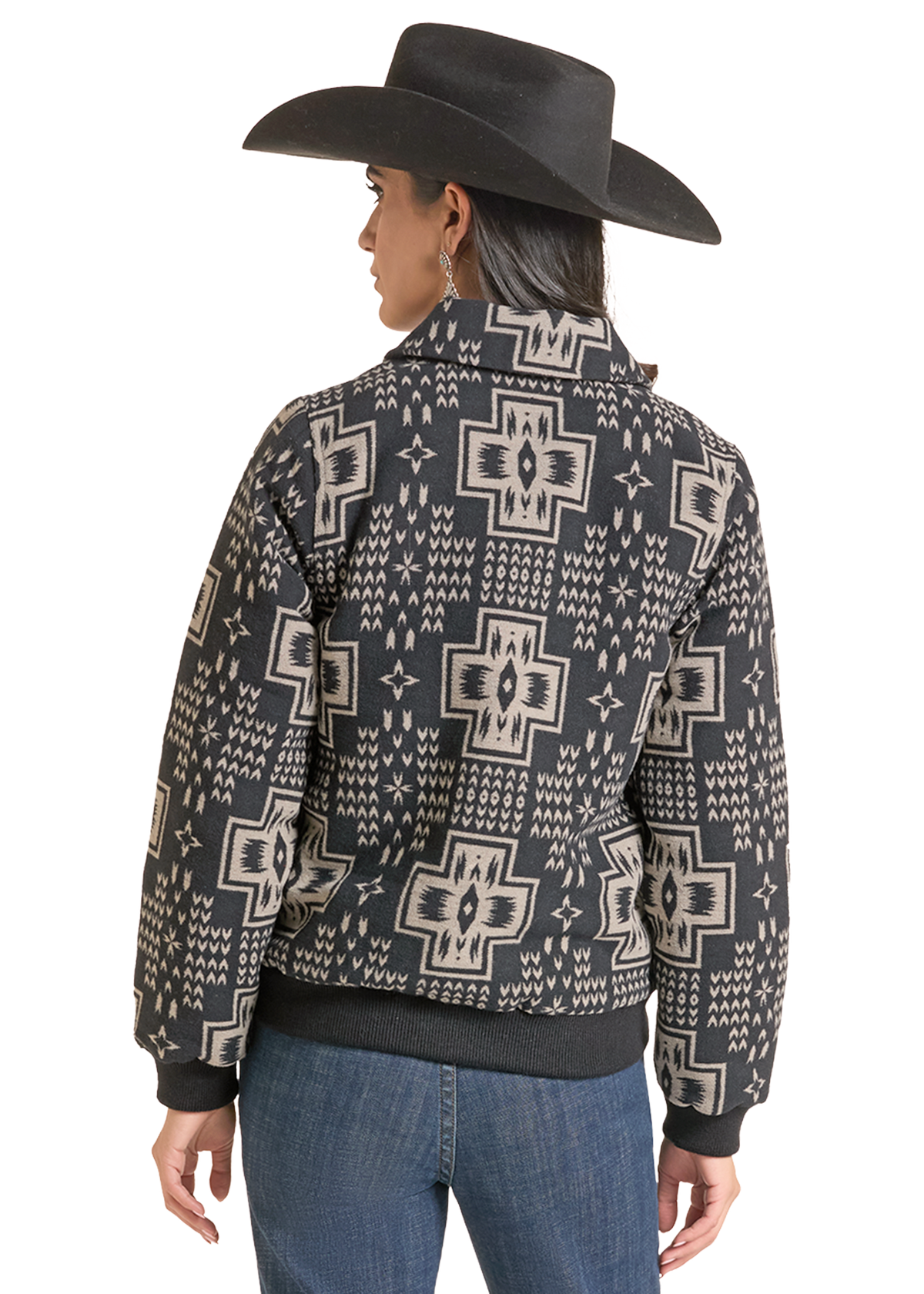A woman shown from the back wearing a black and beige southwestern-style patterned jacket, a black cowboy hat, and blue jeans.