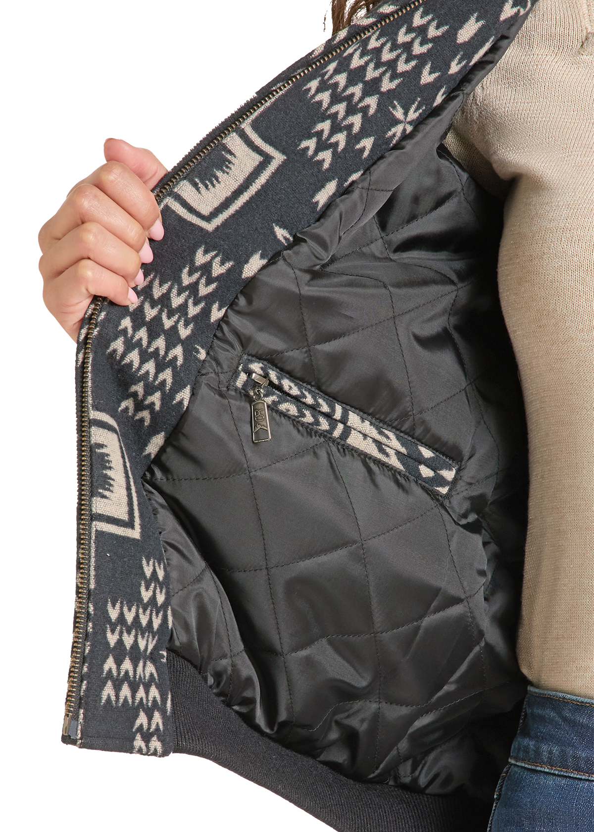 Close-up of a person opening a dark patterned jacket to show a black quilted interior with a zippered pocket.