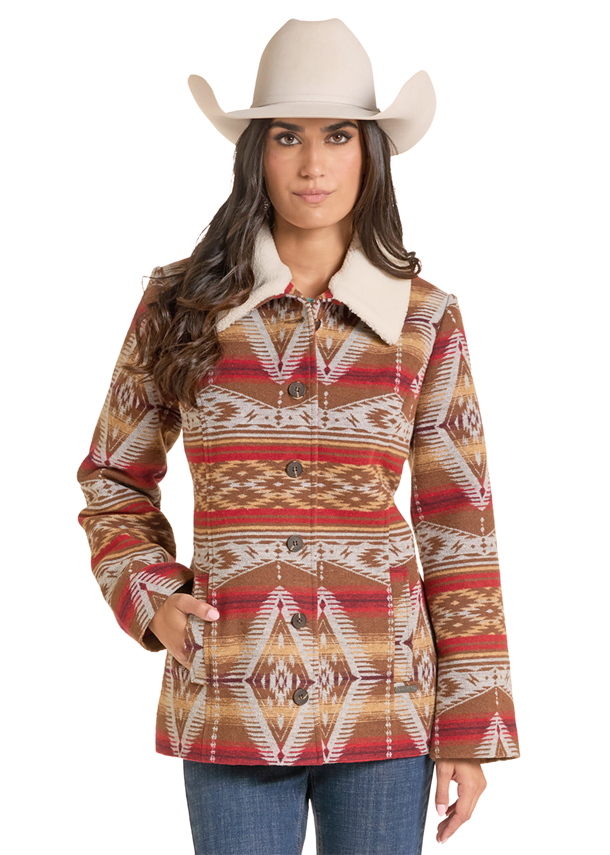 A woman wearing a western-style patterned jacket with a cream collar, a beige cowboy hat, and blue jeans.