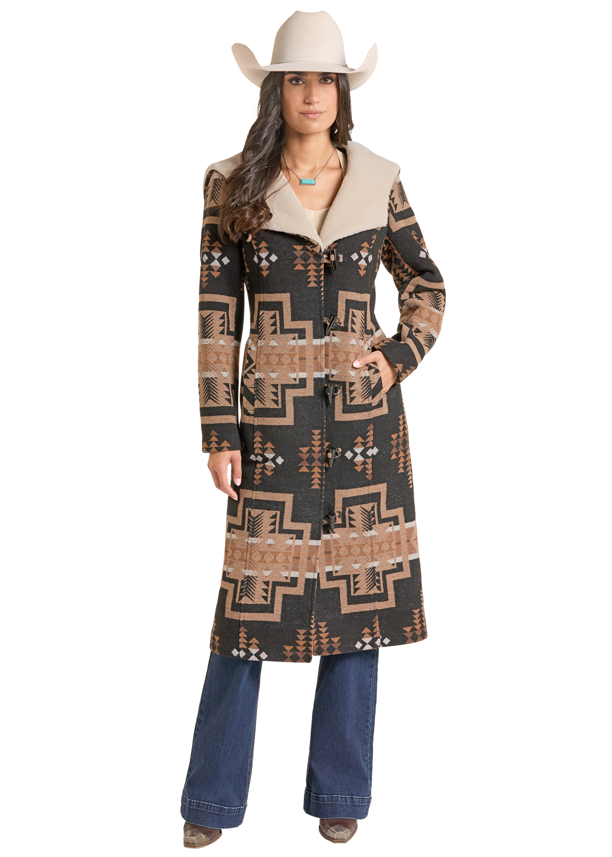 A woman modeling a long western-style coat with a Southwestern geometric pattern in black.