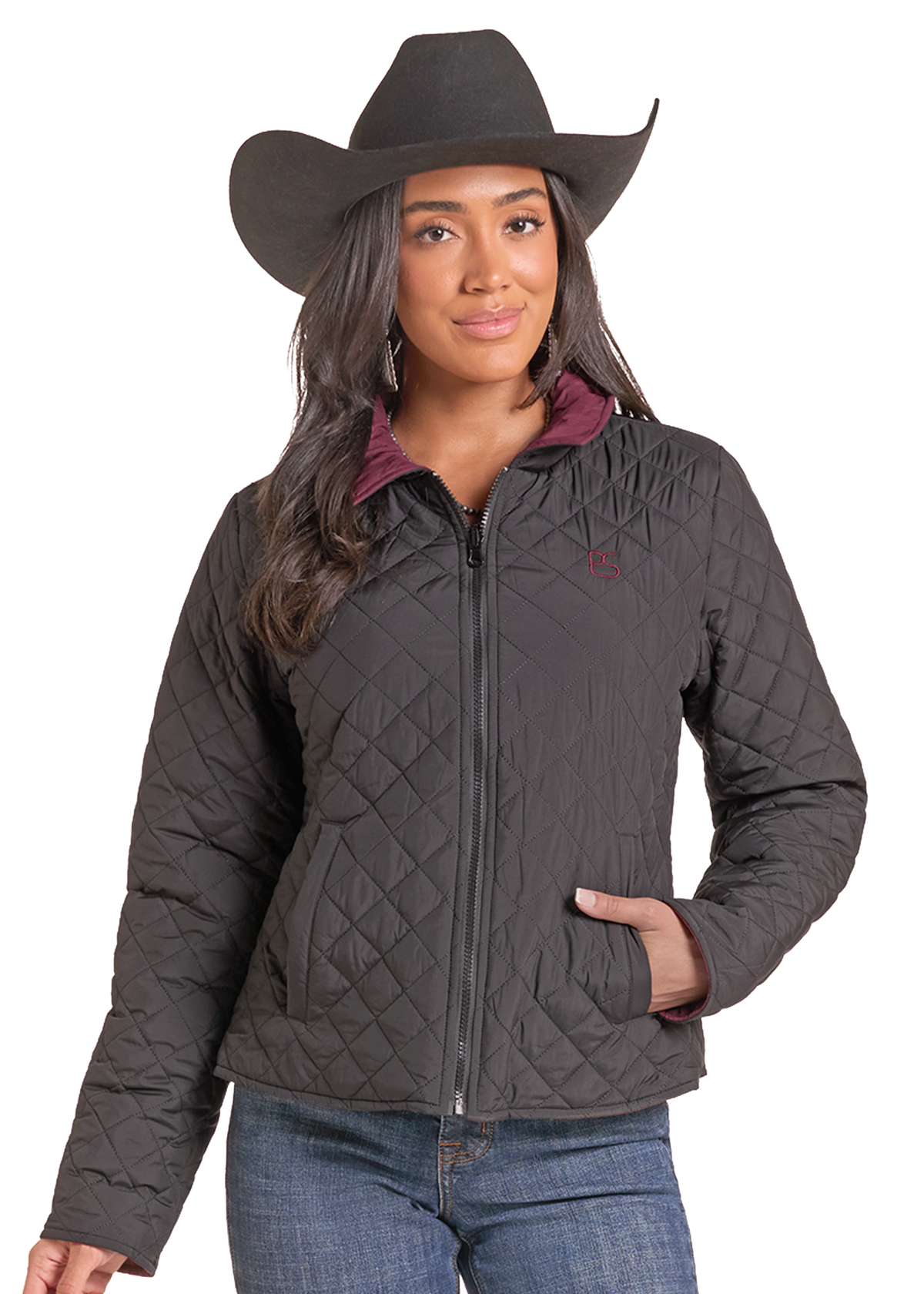 Woman wearing a black quilted zip up jacket with a cowboy hat and jeans. 