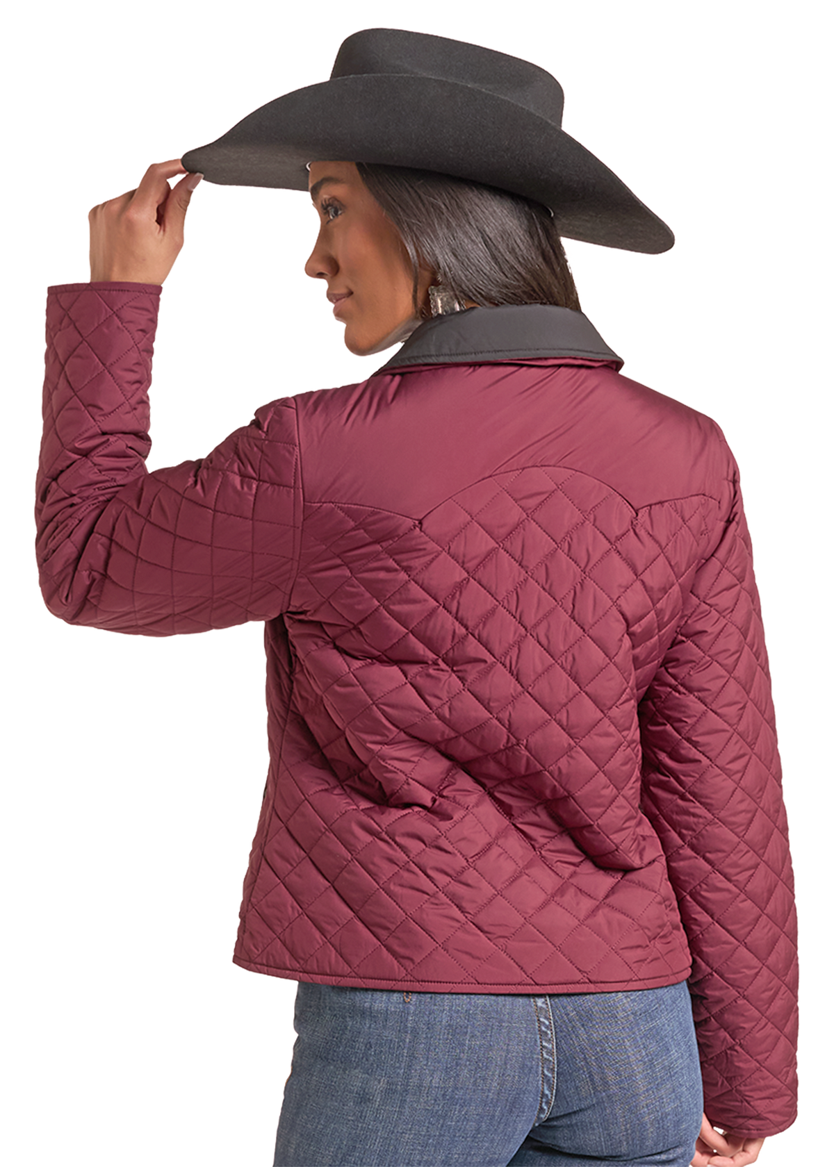 The back of a Woman wearing a wine quilted zip up jacket with a cowboy hat and jeans. 