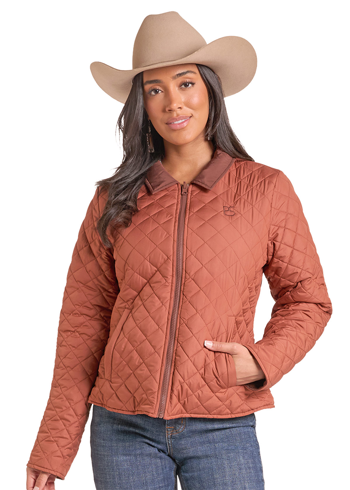 A woman wearing a rust-colored diamond-quilted zip-up jacket, a tan cowboy hat, and blue jeans.
