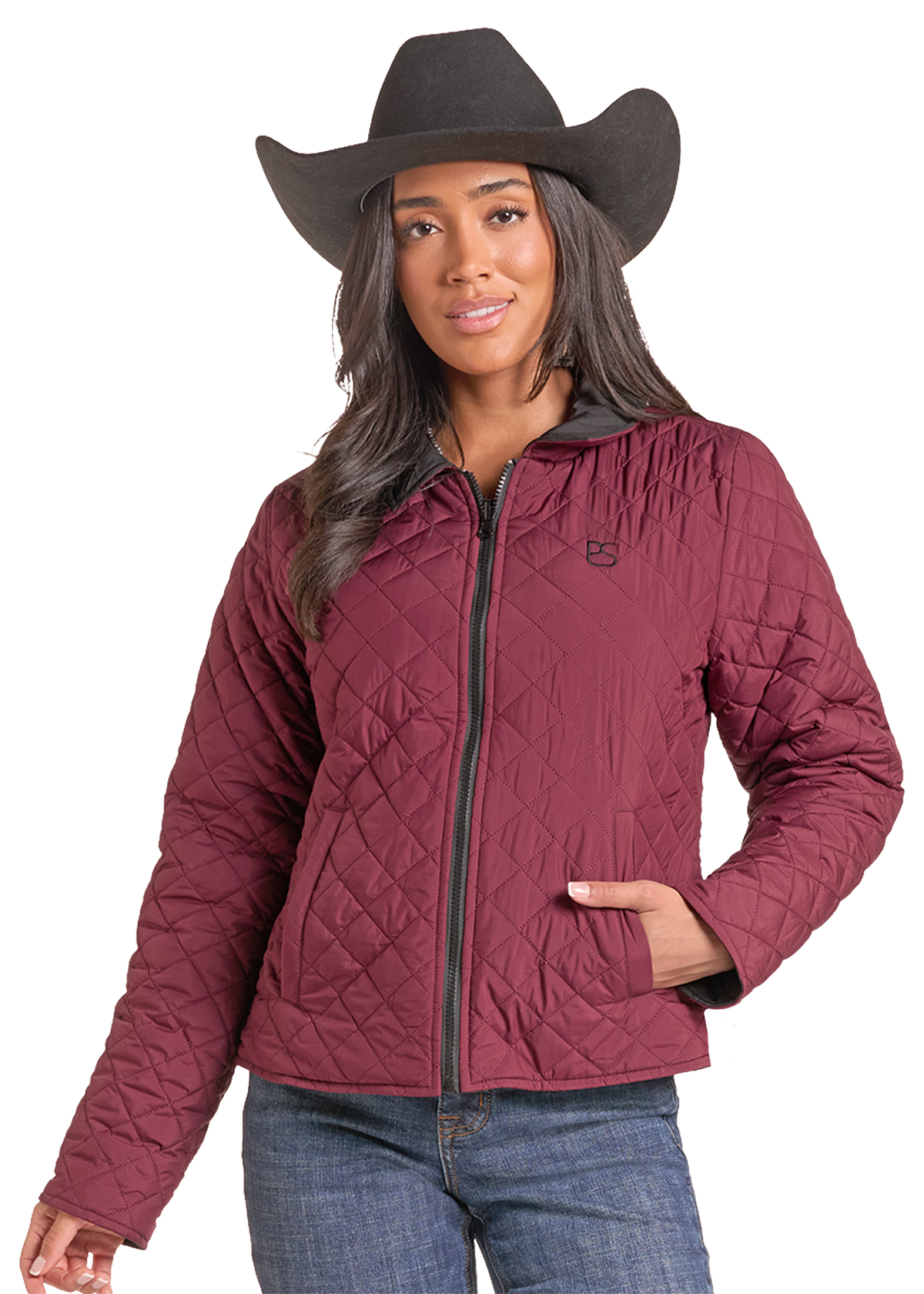 Woman wearing a red quilted zip up jacket with a cowboy hat and jeans. 