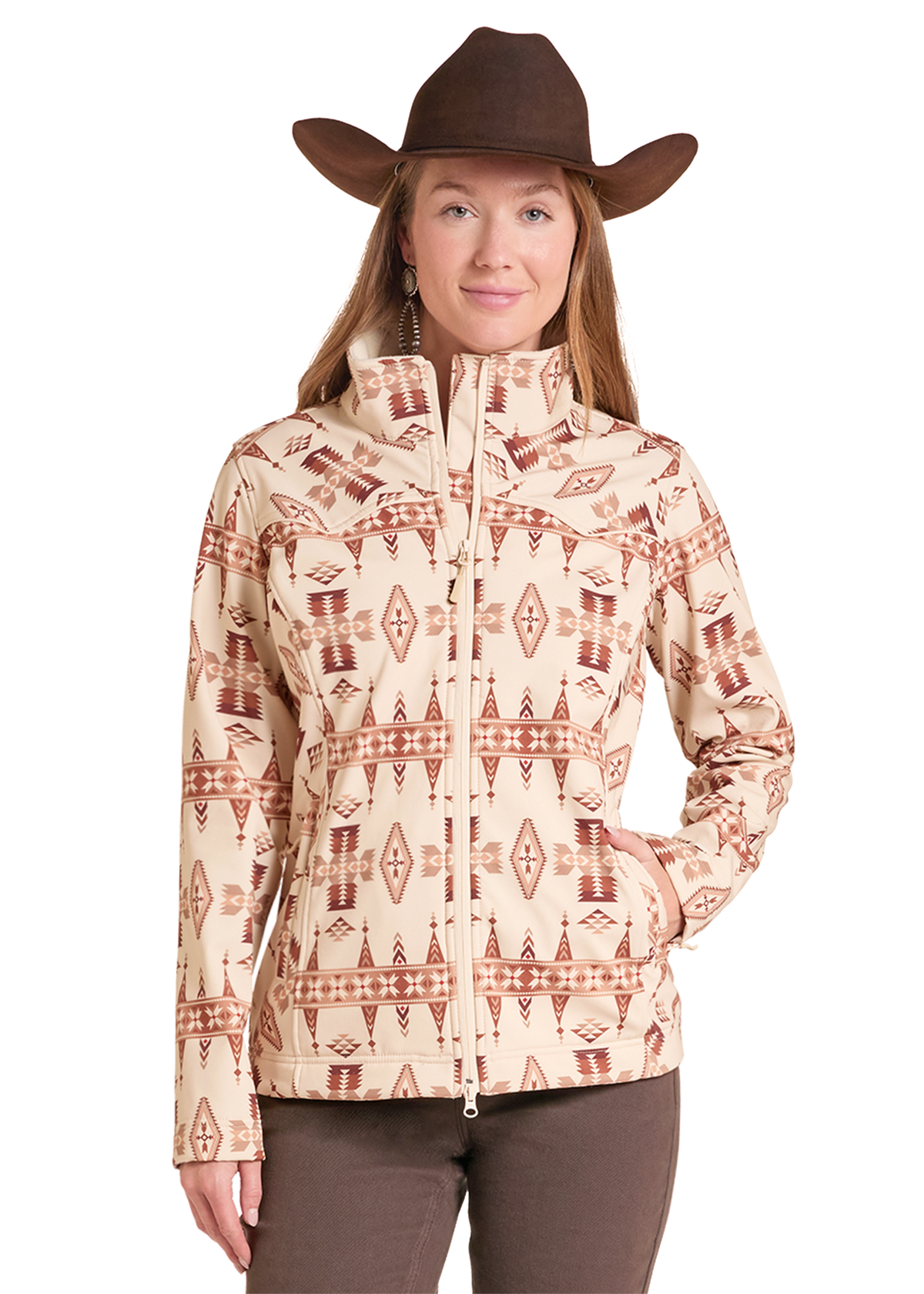 Woman wearing soft shell Aztec jacket with brown pants and a cowboy hat. 