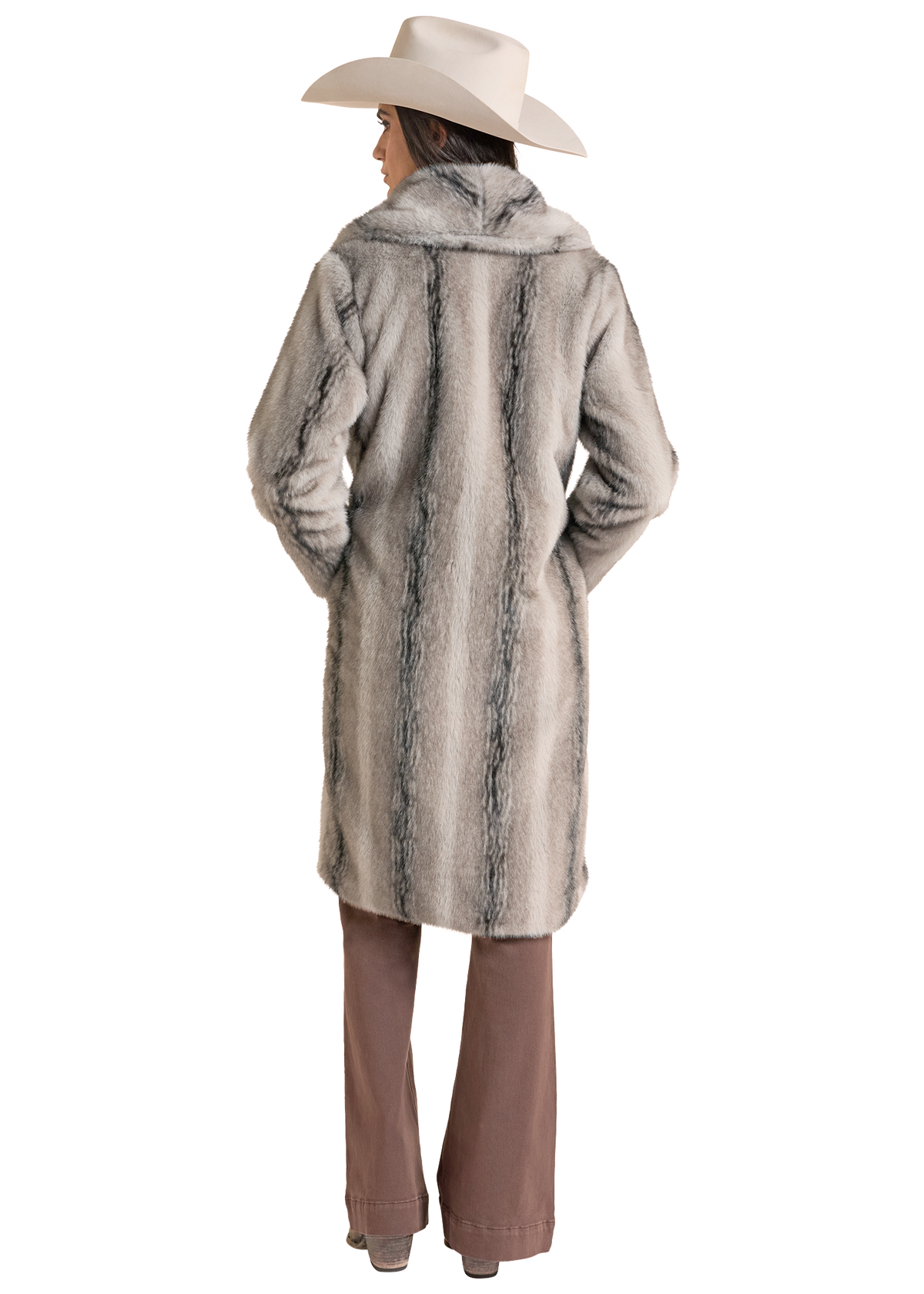 The back of a woman in a  light gray faux fur coat with darker gray marbling, styled with a beige cowboy hat and brown pants.