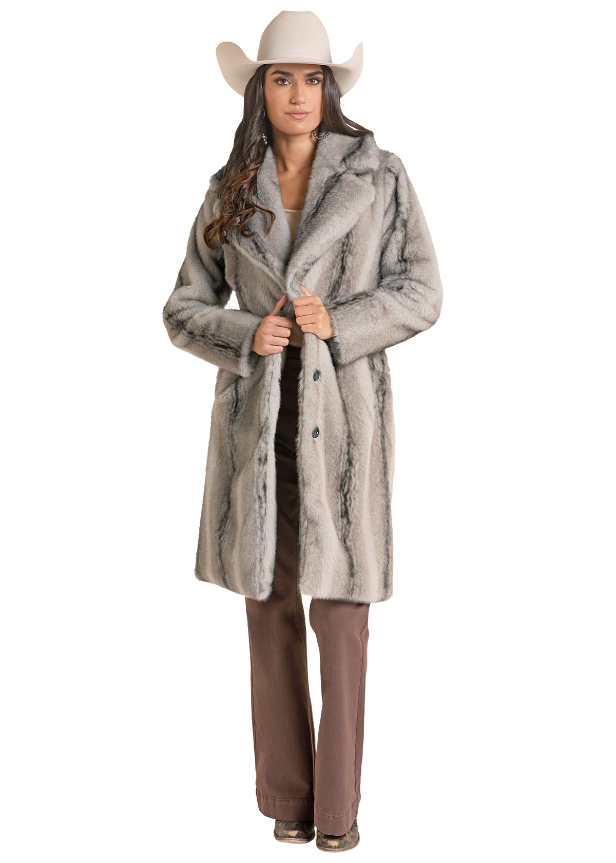 A woman in a  light gray faux fur coat with darker gray marbling, styled with a beige cowboy hat and brown pants.