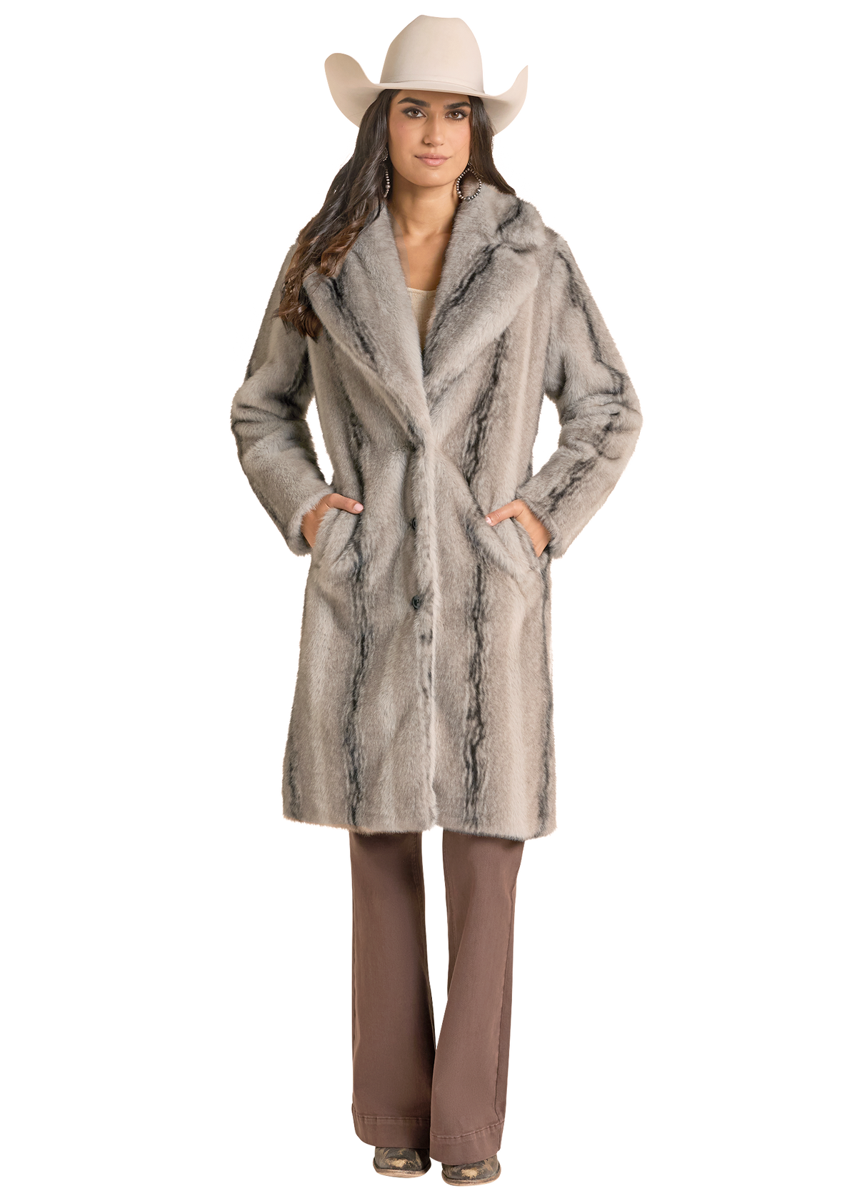 A woman in a  light gray faux fur coat with darker gray marbling, styled with a beige cowboy hat and brown pants.