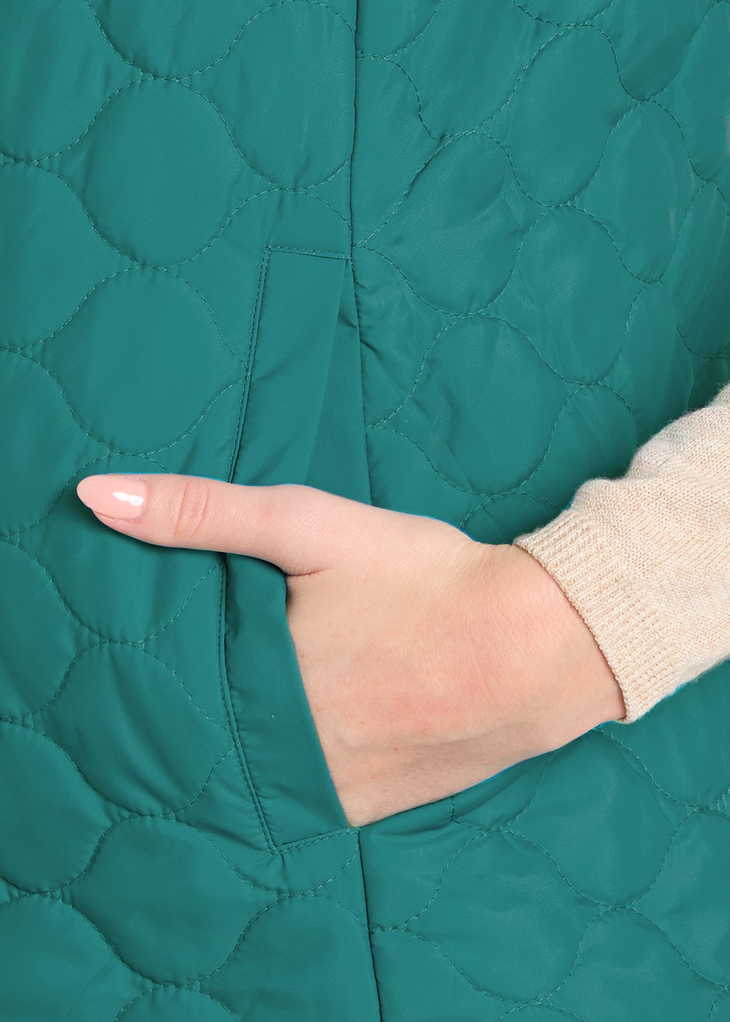 Close-up of a hand touching a teal quilted fabric surface