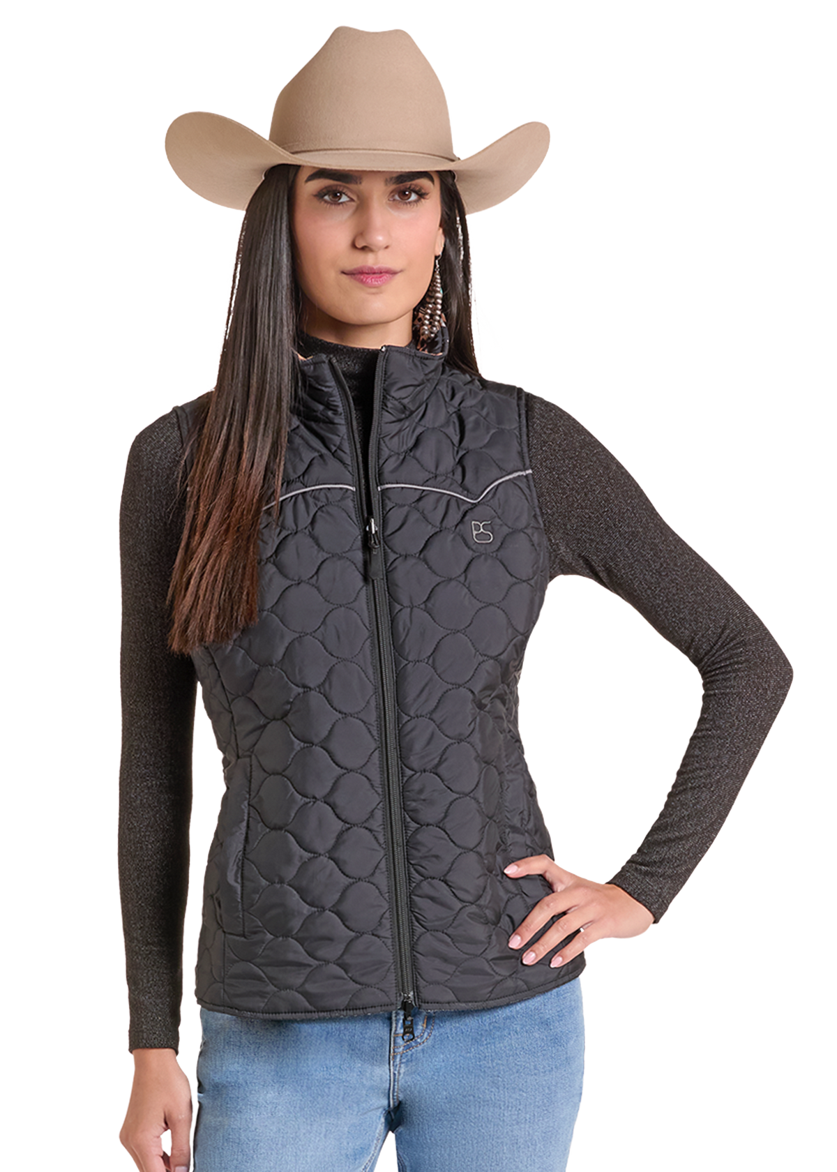 A woman modeling a dark gray quilted zip-up vest over a dark long-sleeve shirt, wearing a tan cowboy hat and blue jeans.