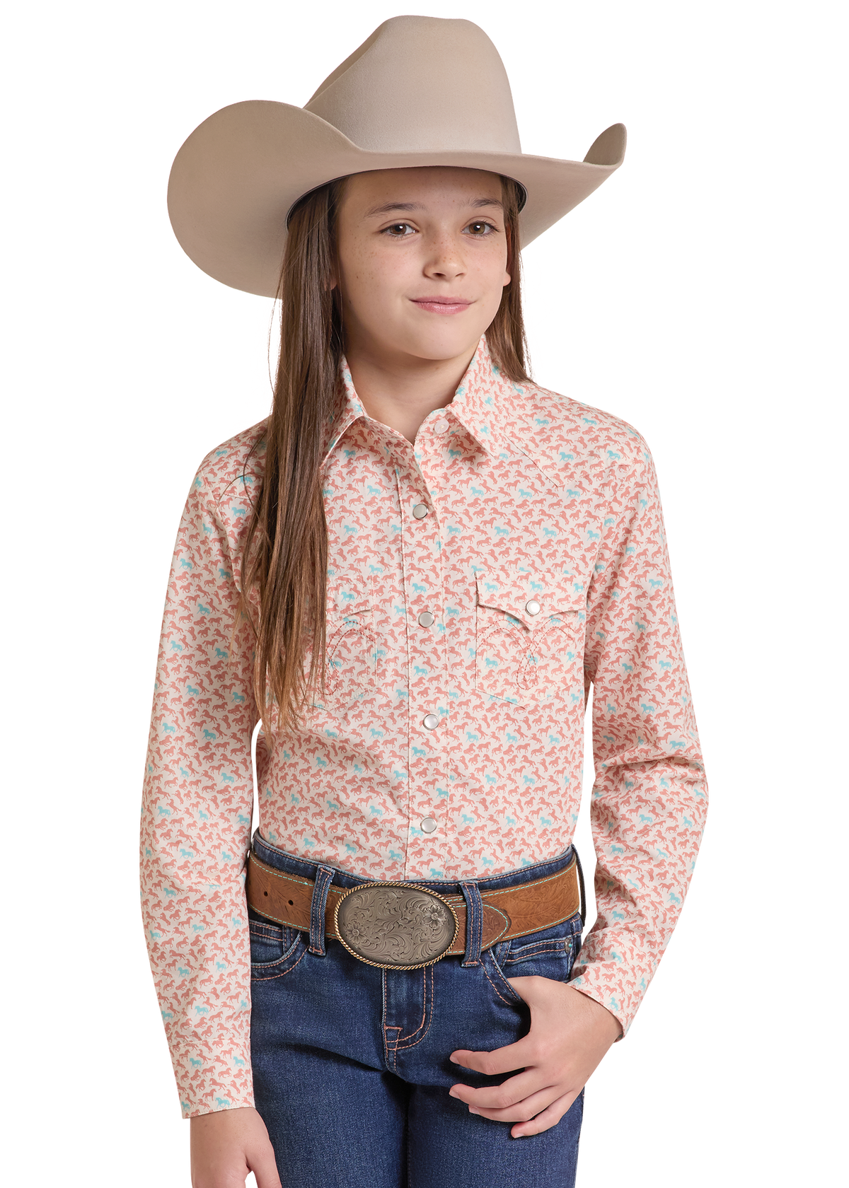A young girl wearing a western-style long-sleeve button-up shirt with a peach and light blue pattern, paired with a tan cowboy hat, brown belt, and blue jeans.