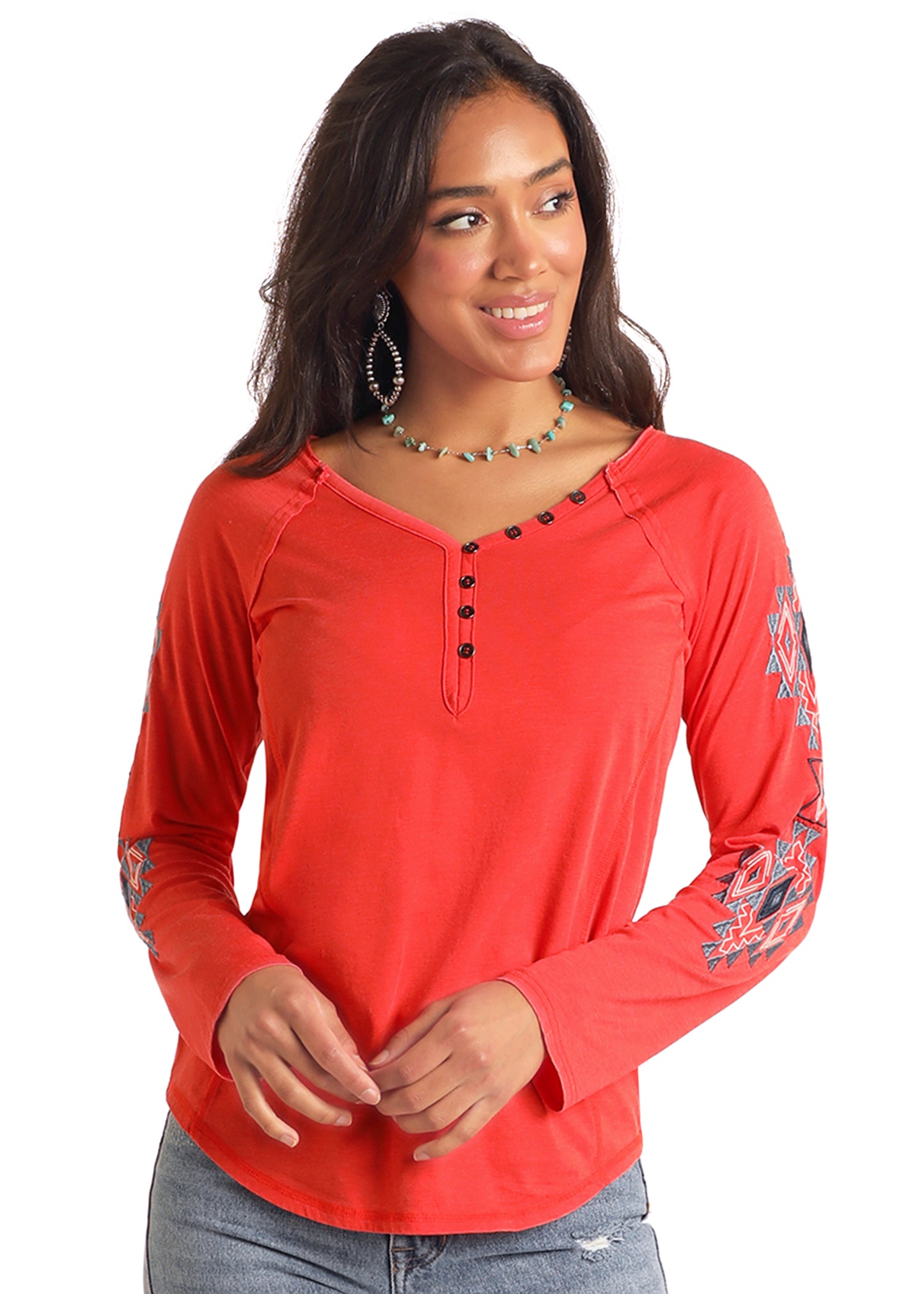 Woman wearing a red long-sleeve shirt with floral designs on sleeves against a white background