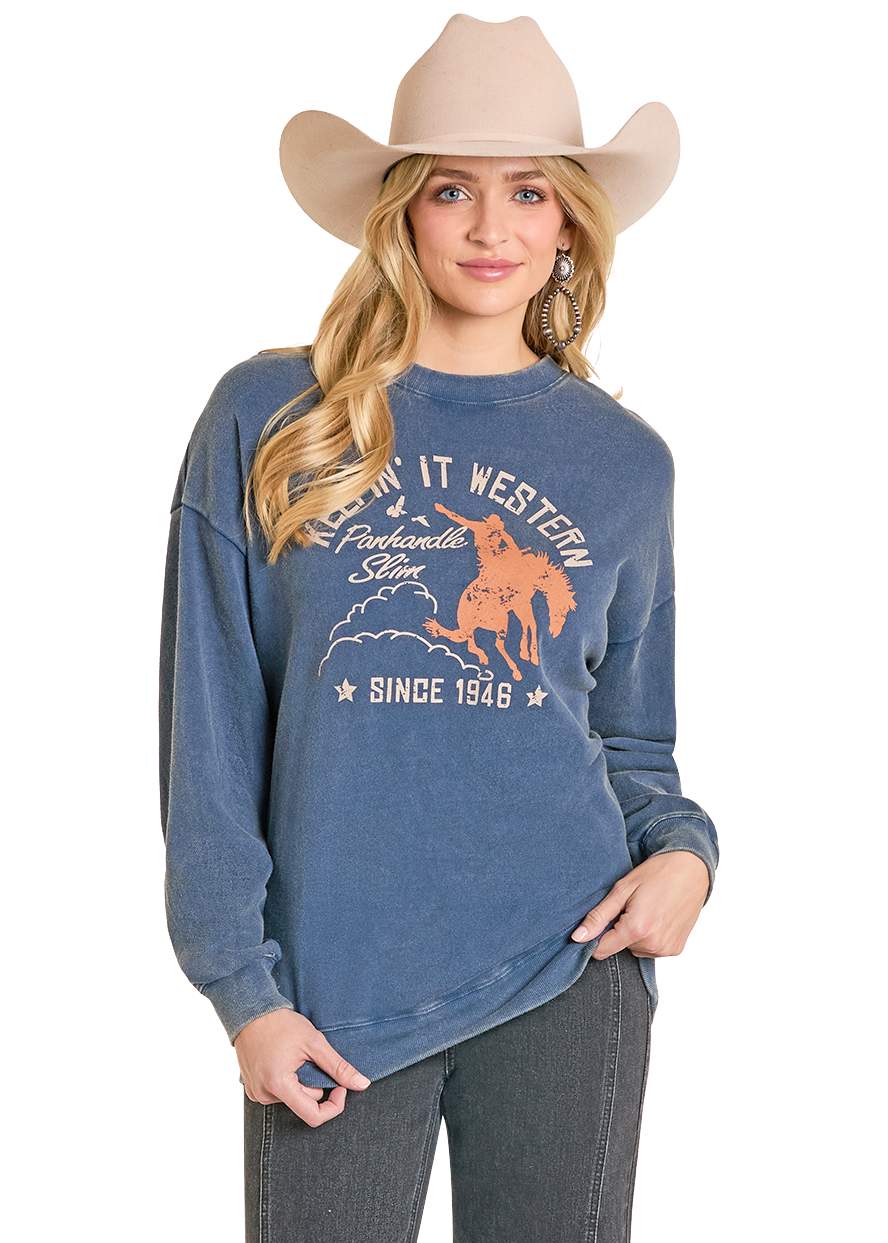 Woman wearing a blue long-sleeve shirt with a graphic design and gray pants on a white background