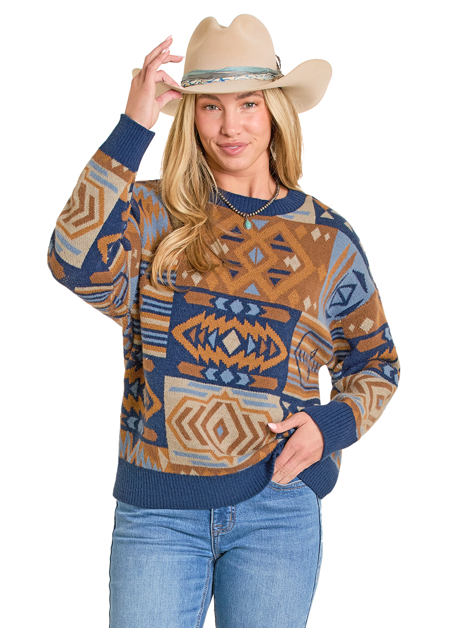 Woman wearing a patterned sweater and jeans with a cowboy hat on a white background