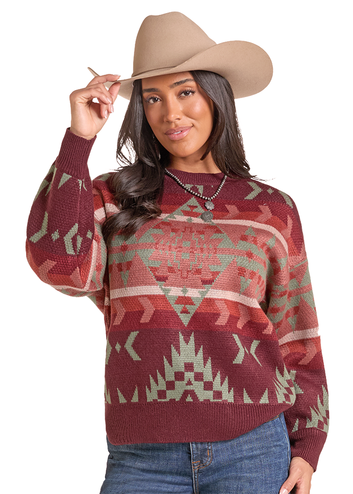 A woman wearing a maroon knit sweater with a Southwestern geometric pattern in sage green and beige, paired with a tan cowboy hat and blue jeans.