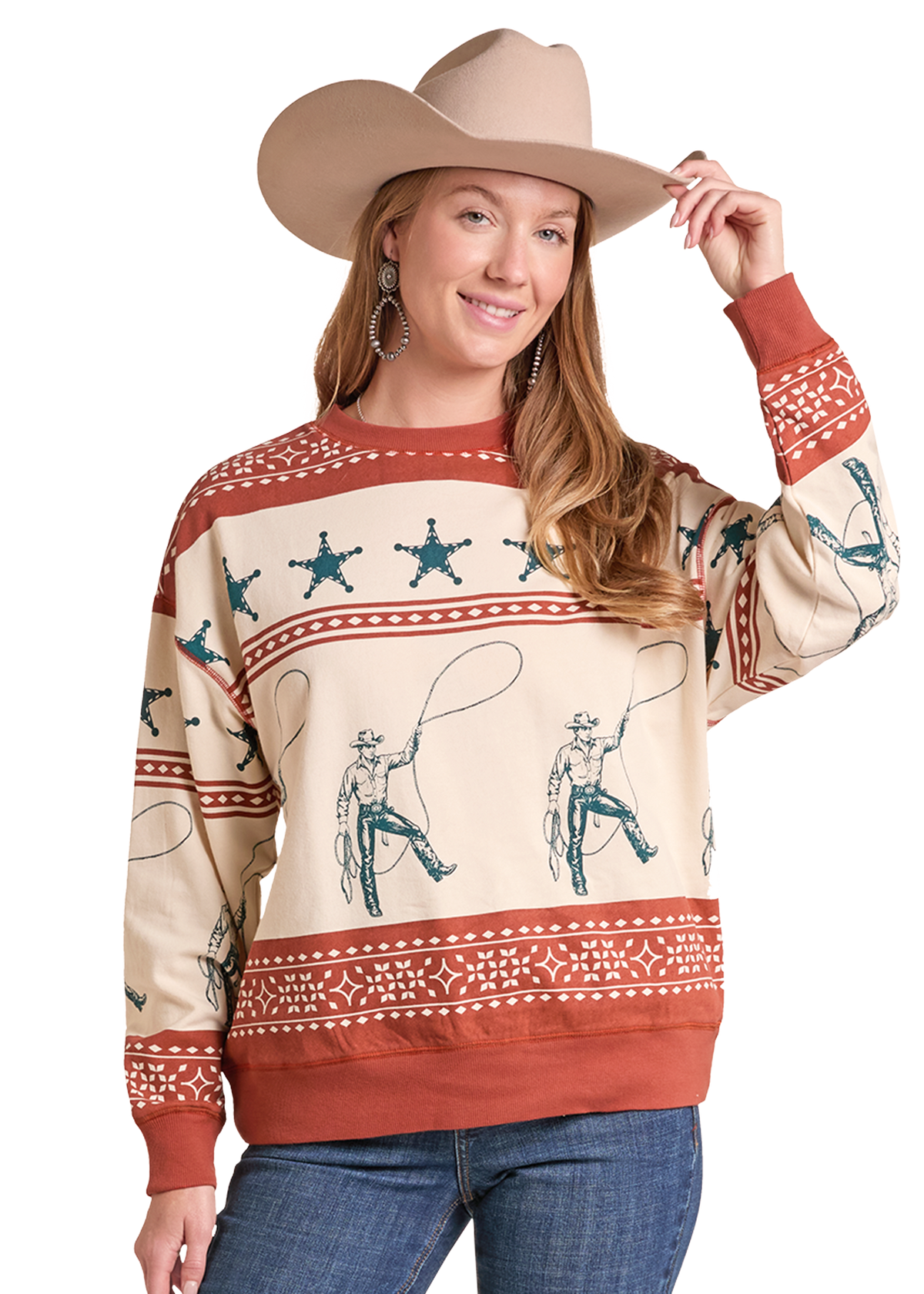 A woman wearing a beige cowboy hat and a cream-colored long-sleeve sweater with a rustic western print featuring brown cowboys with lasso straps, blue star motifs, and rust-red horizontal bands.