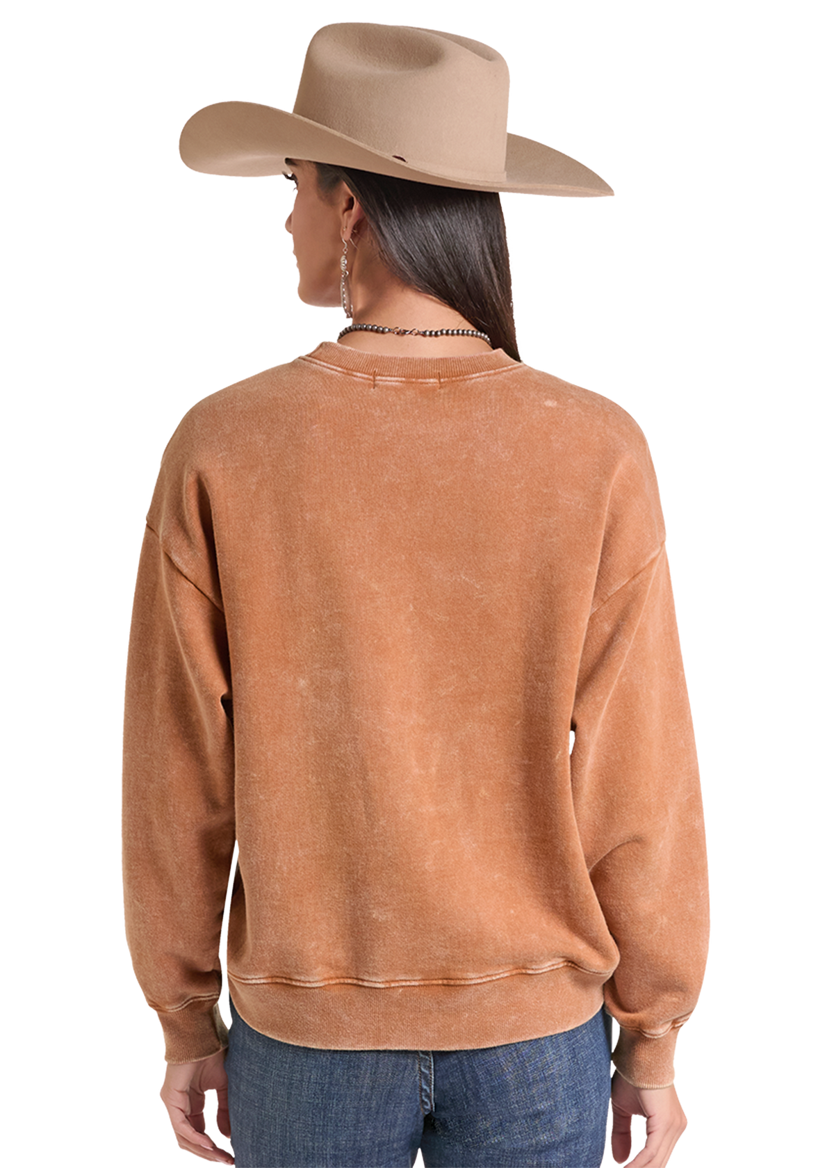 A woman shown from the back wearing a washed tan crewneck sweatshirt, a beige cowboy hat, and blue jeans against a white background.