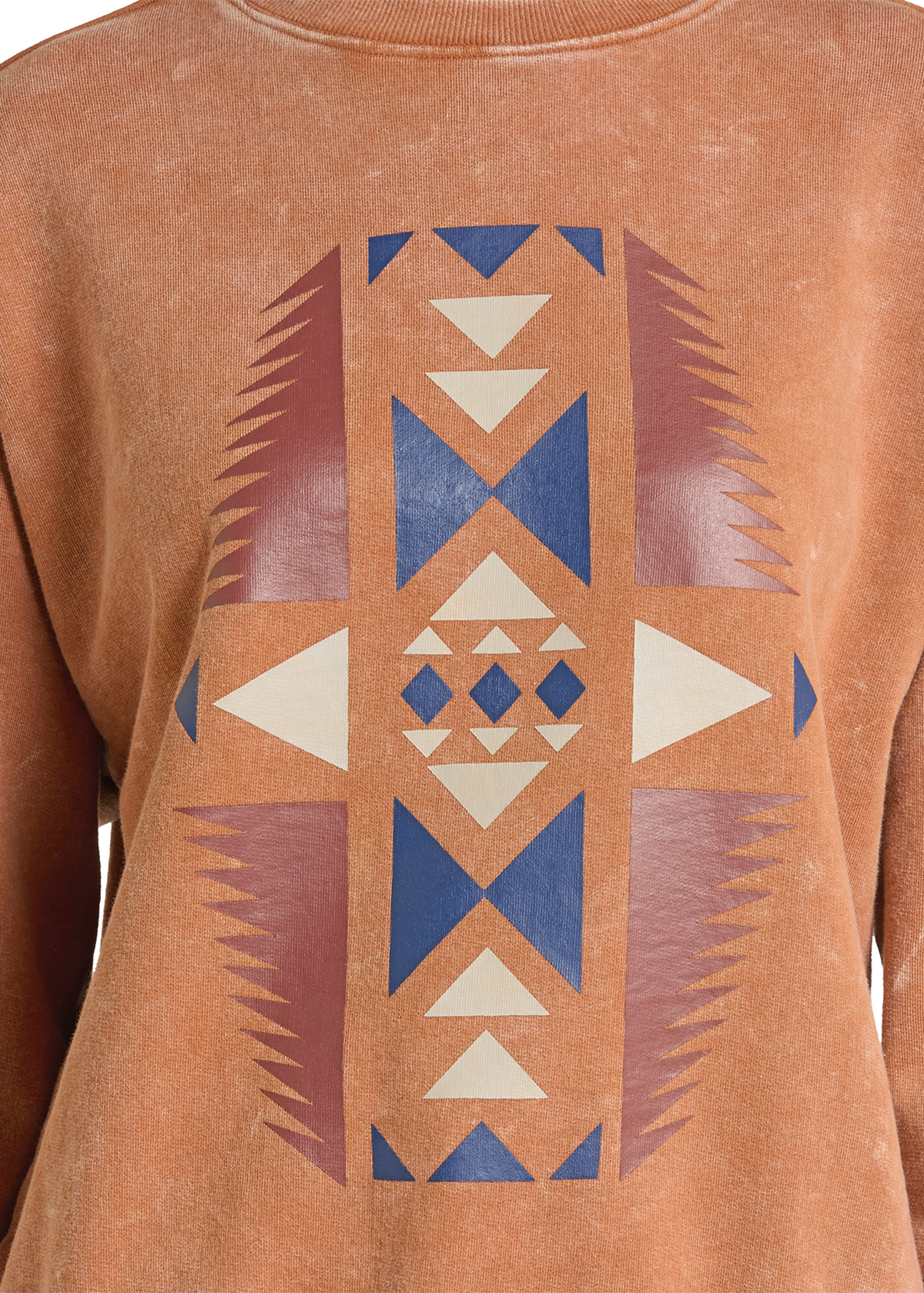 A close-up of a rust-orange crewneck sweatshirt featuring a large geometric tribal-style print in blue, dusty rose, and cream on the front.