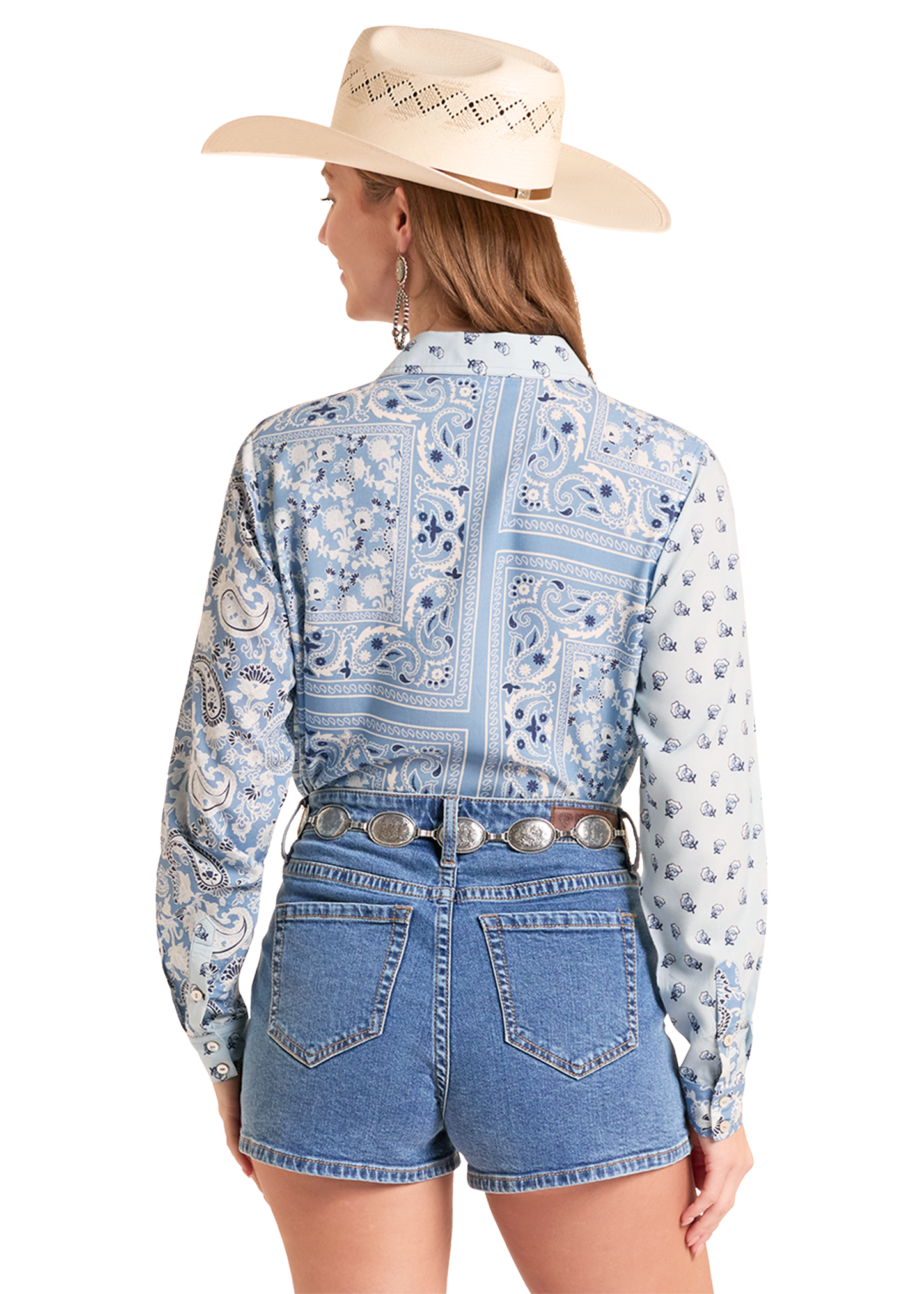 Woman wearing a blue patterned shirt and denim shorts with a cowboy hat on a white background