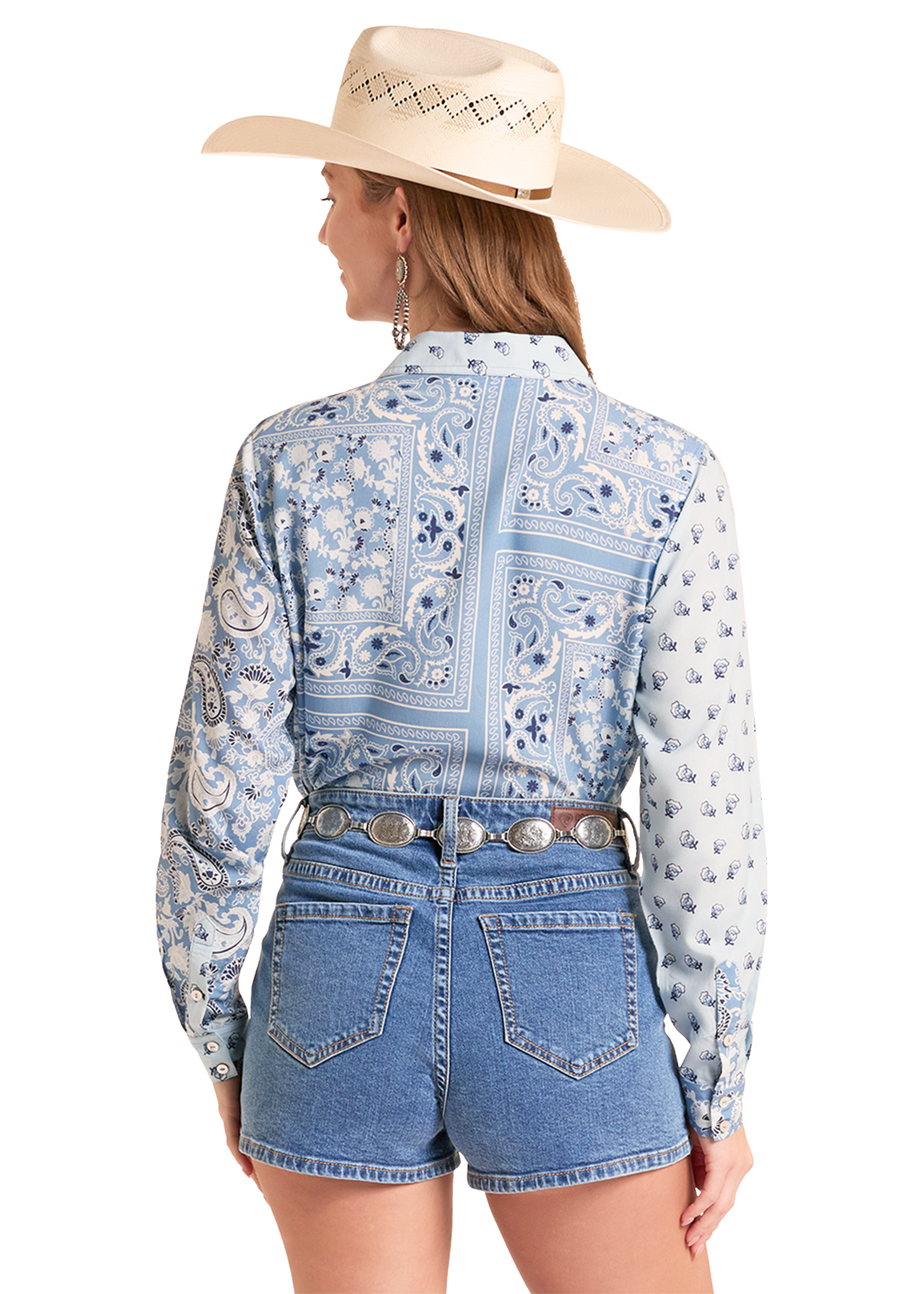 Woman wearing a blue patterned shirt and denim shorts with a cowboy hat on a white background