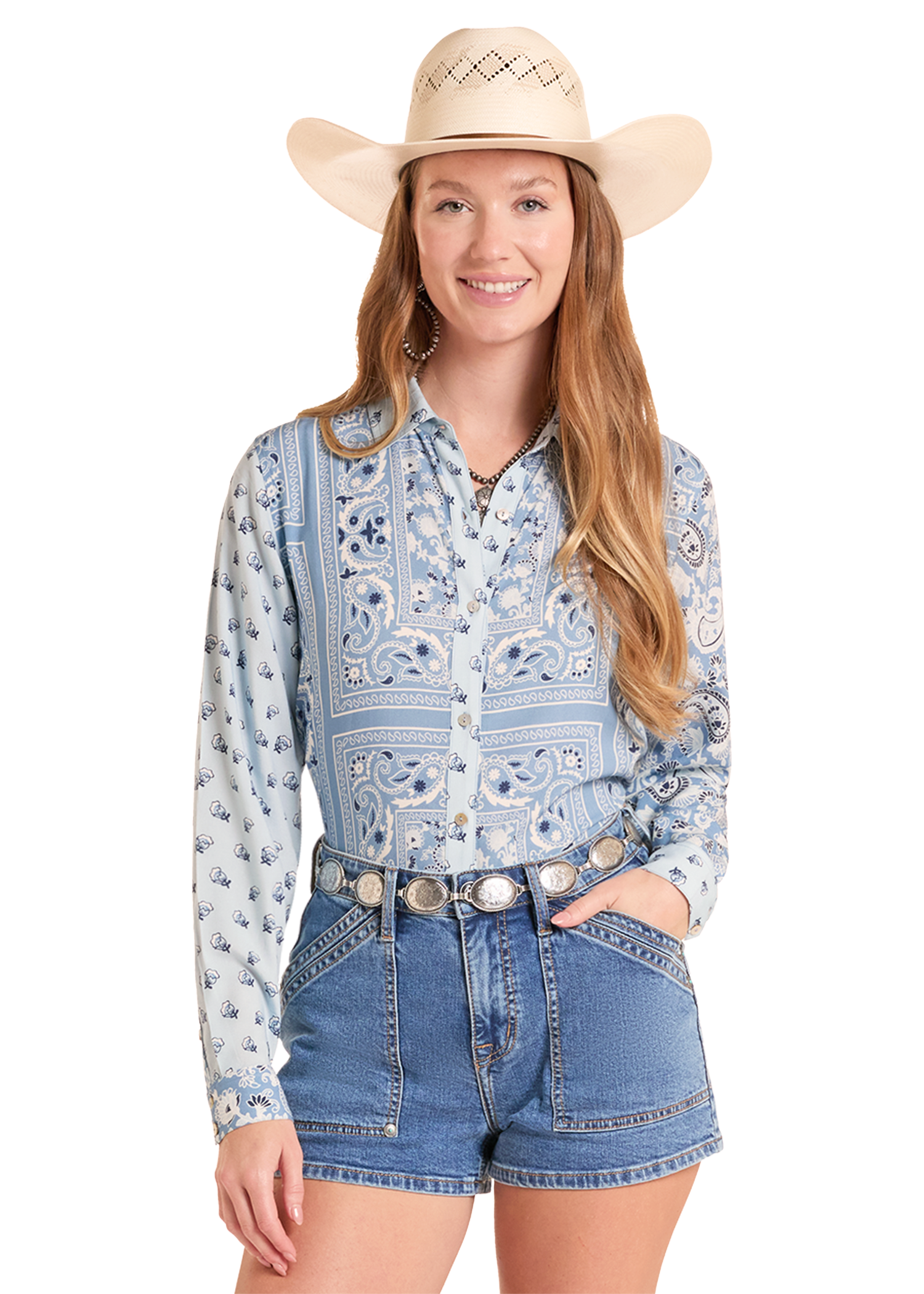 Woman wearing a patterned shirt, denim shorts, and a cowboy hat on a white background
