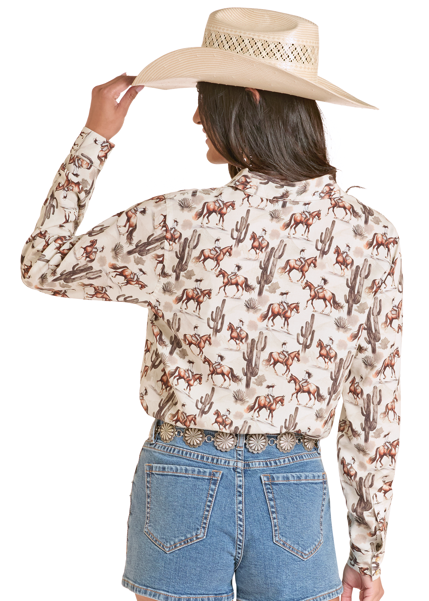 Person wearing a patterned shirt with horses and cacti, holding a cowboy hat on a white background