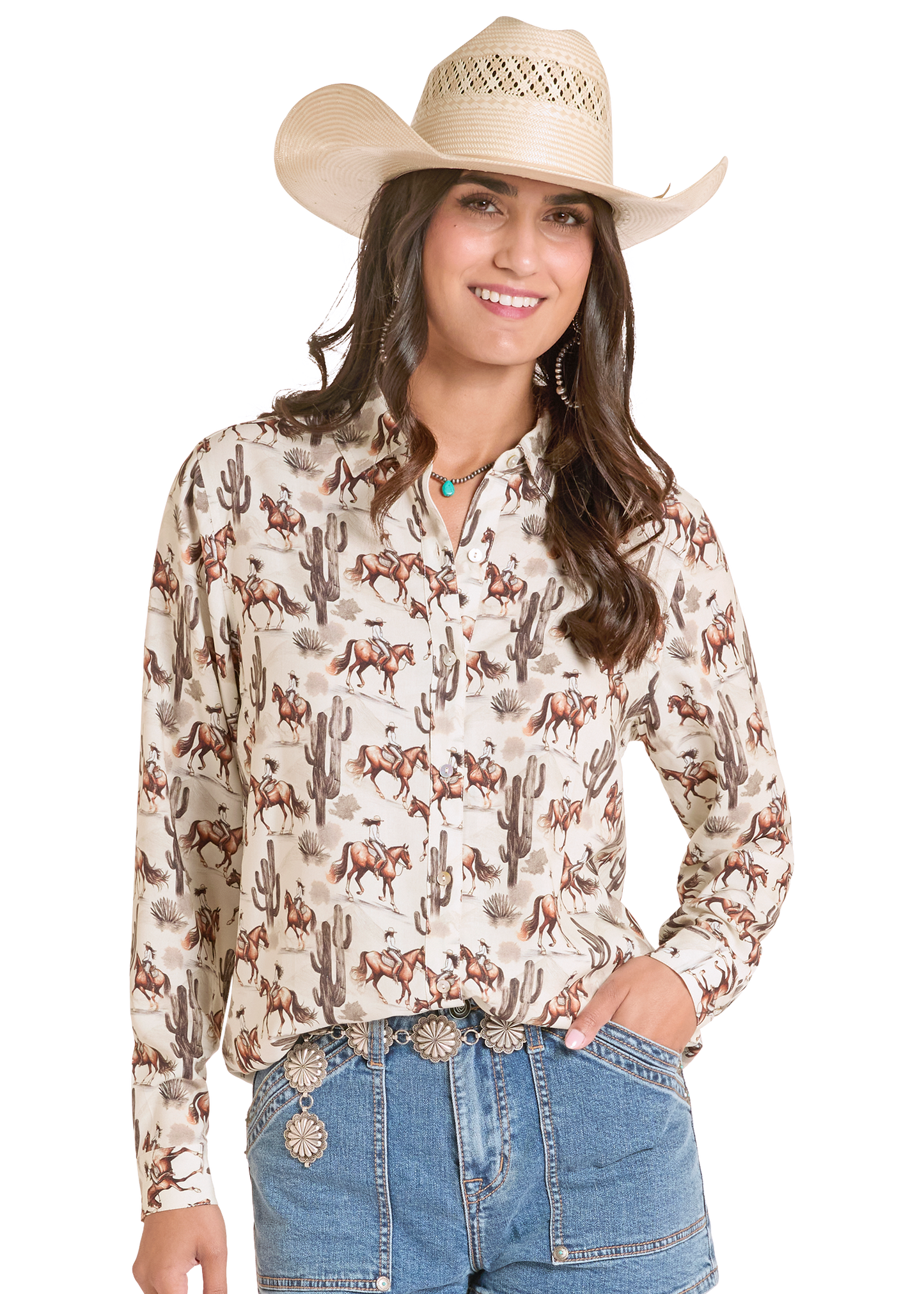 Woman wearing a long-sleeve Western-style shirt with horse and cactus pattern, paired with a cowboy hat and jeans on a white background.